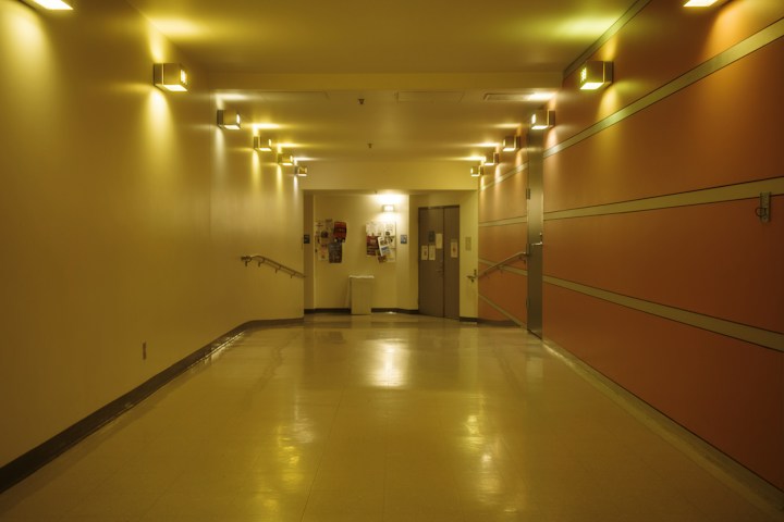 Pasillo de un hospital con puertas al fondo, iluminado con luz natural