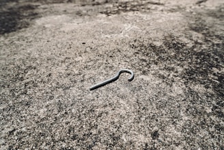 A metal cotter pin lies on a textured surface.