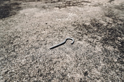 A metal cotter pin lies on a textured surface.