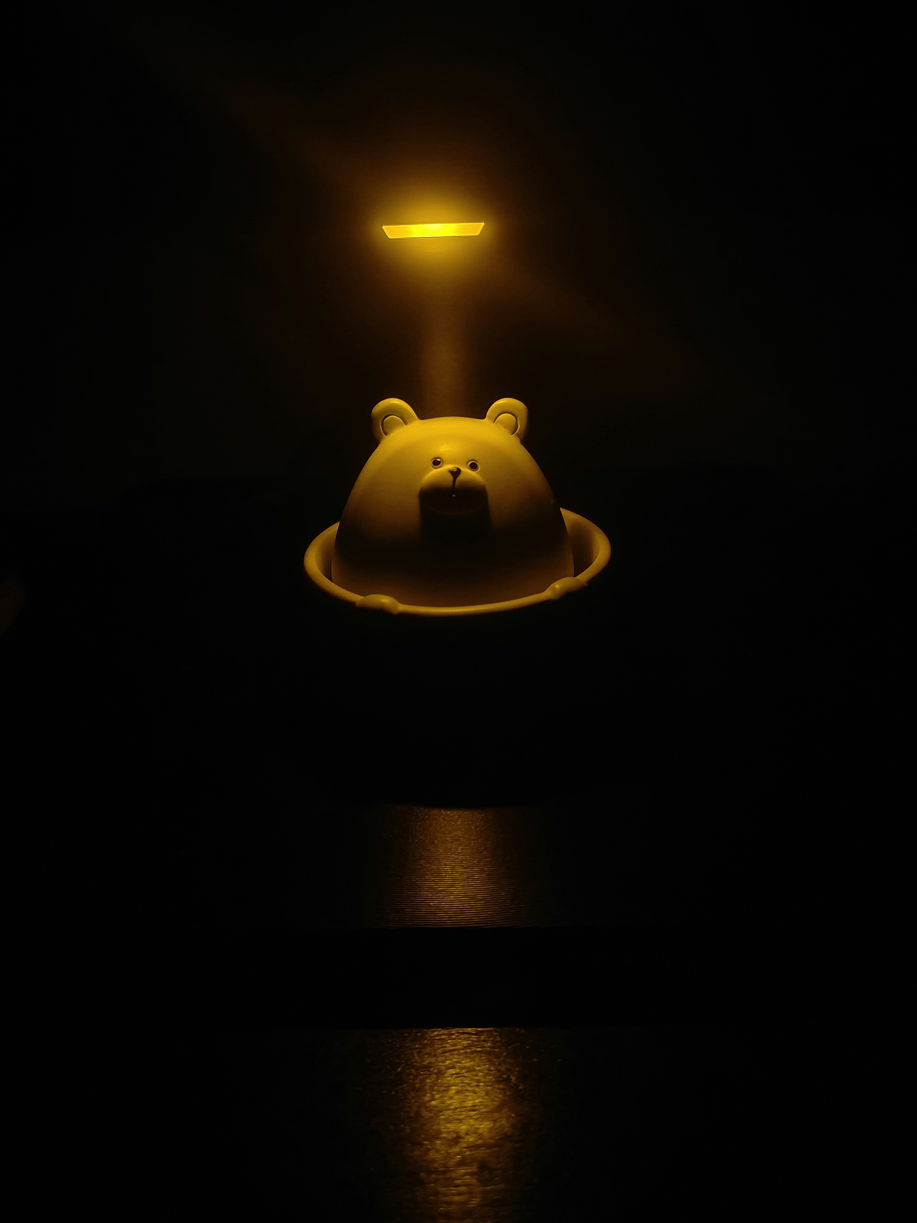 Yellow bear toy illuminated by spotlight in darkness