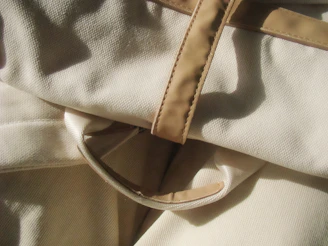 Close-up of cream fabric with tan leather straps.