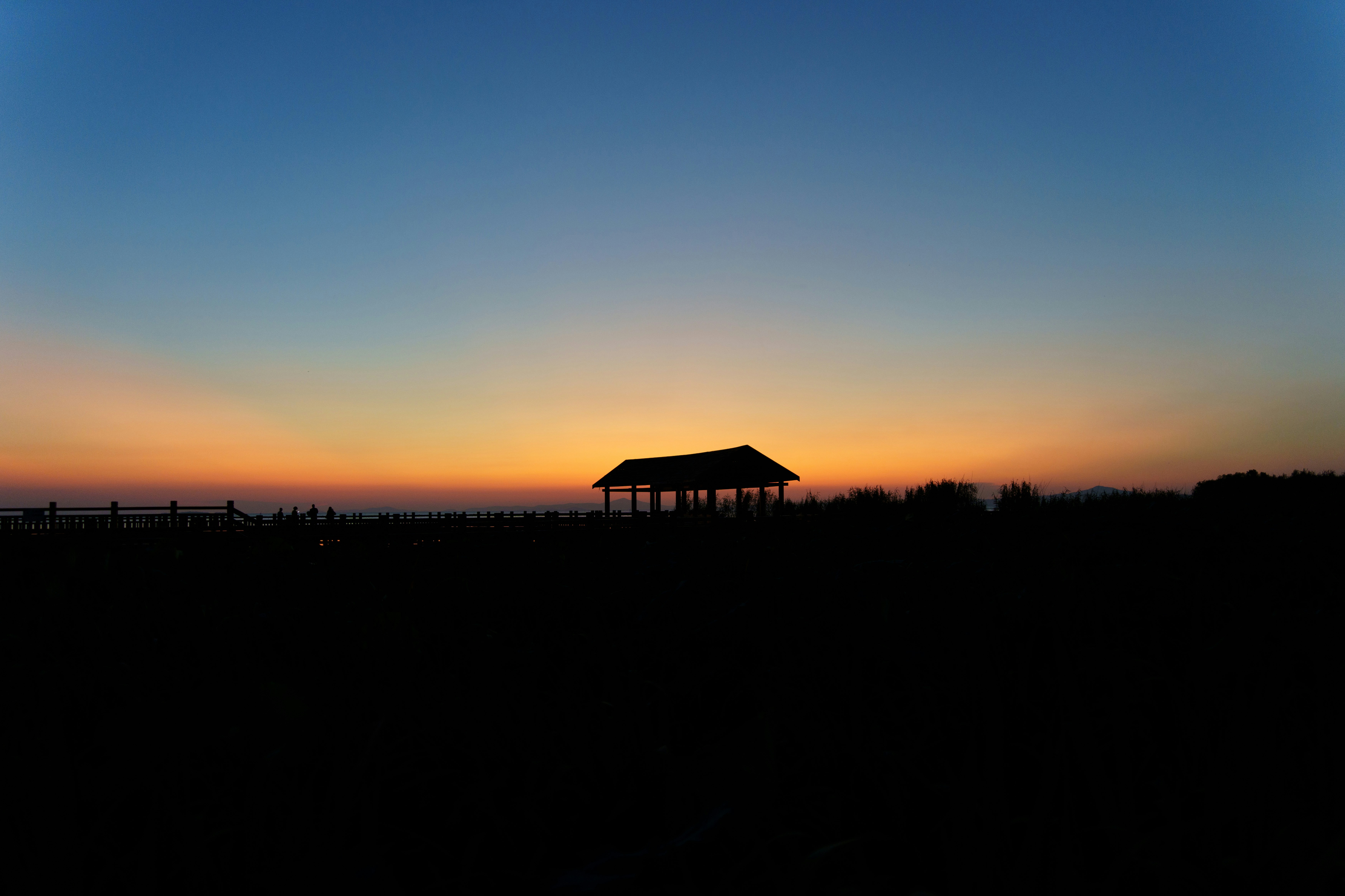 Silhouette of a gazebo against a vibrant sunset sky.
