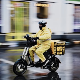 Delivery person on electric scooter in yellow jacket