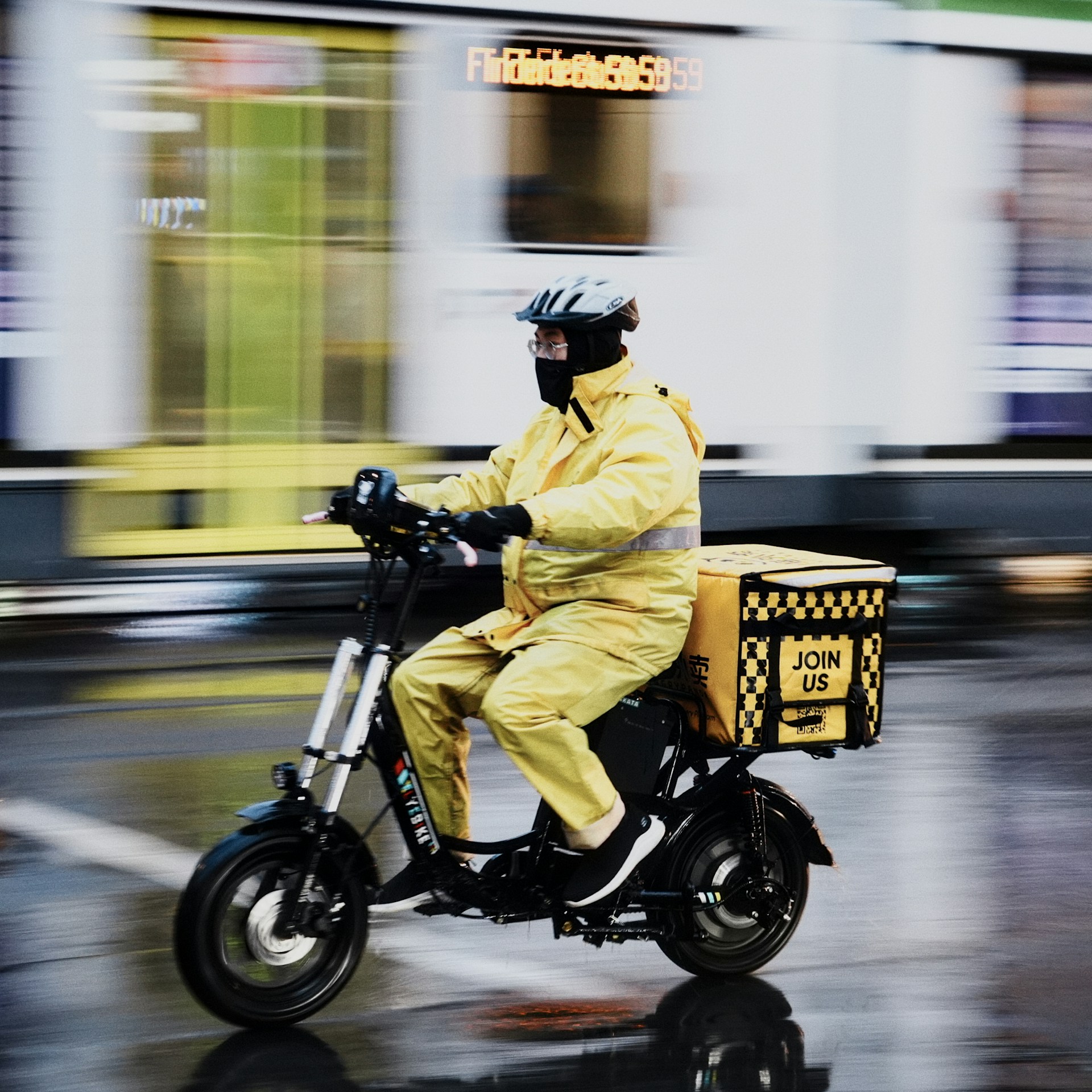 Delivery person on electric scooter in yellow jacket