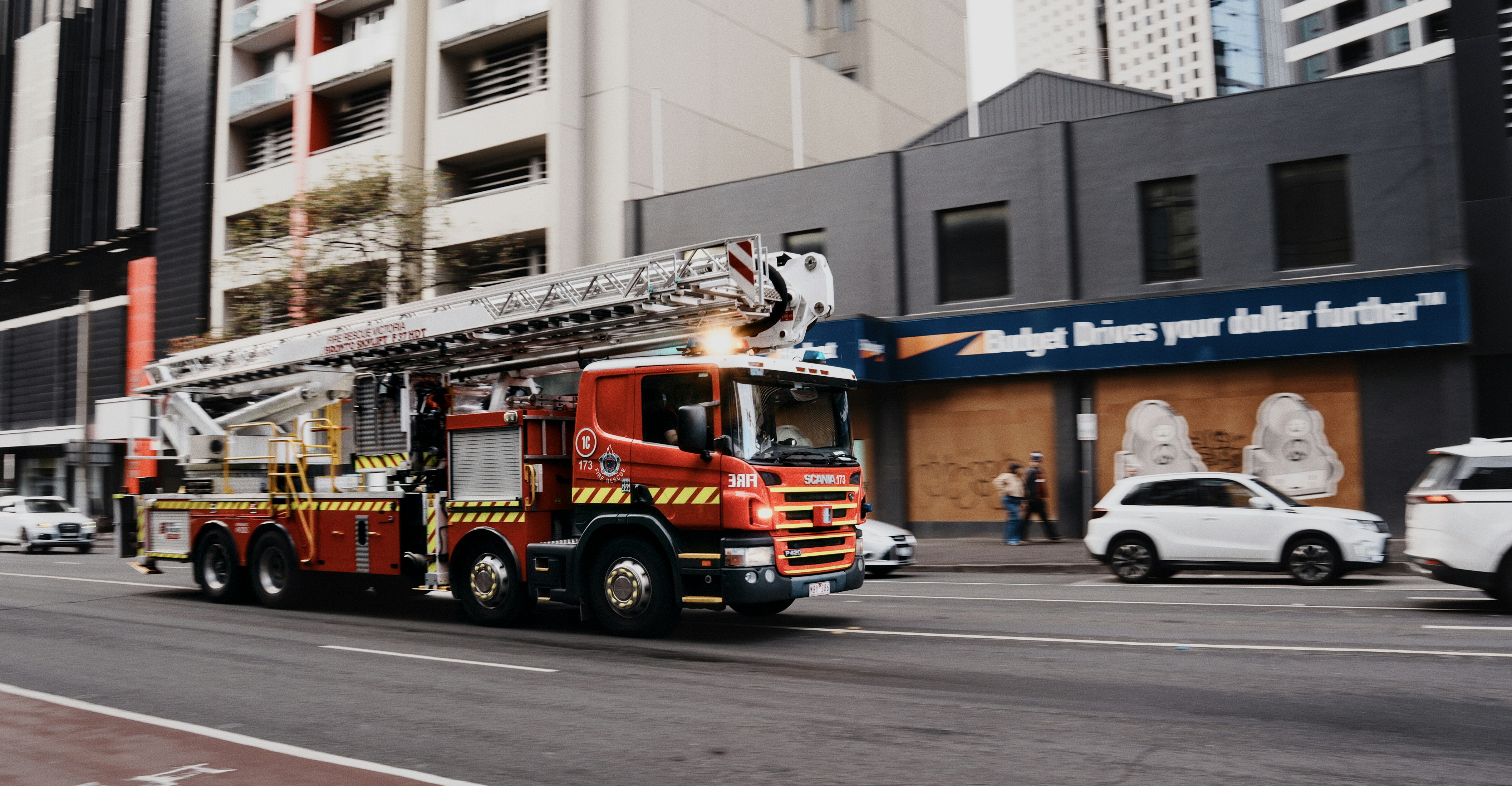 Fire truck with extended ladder drives down city street.