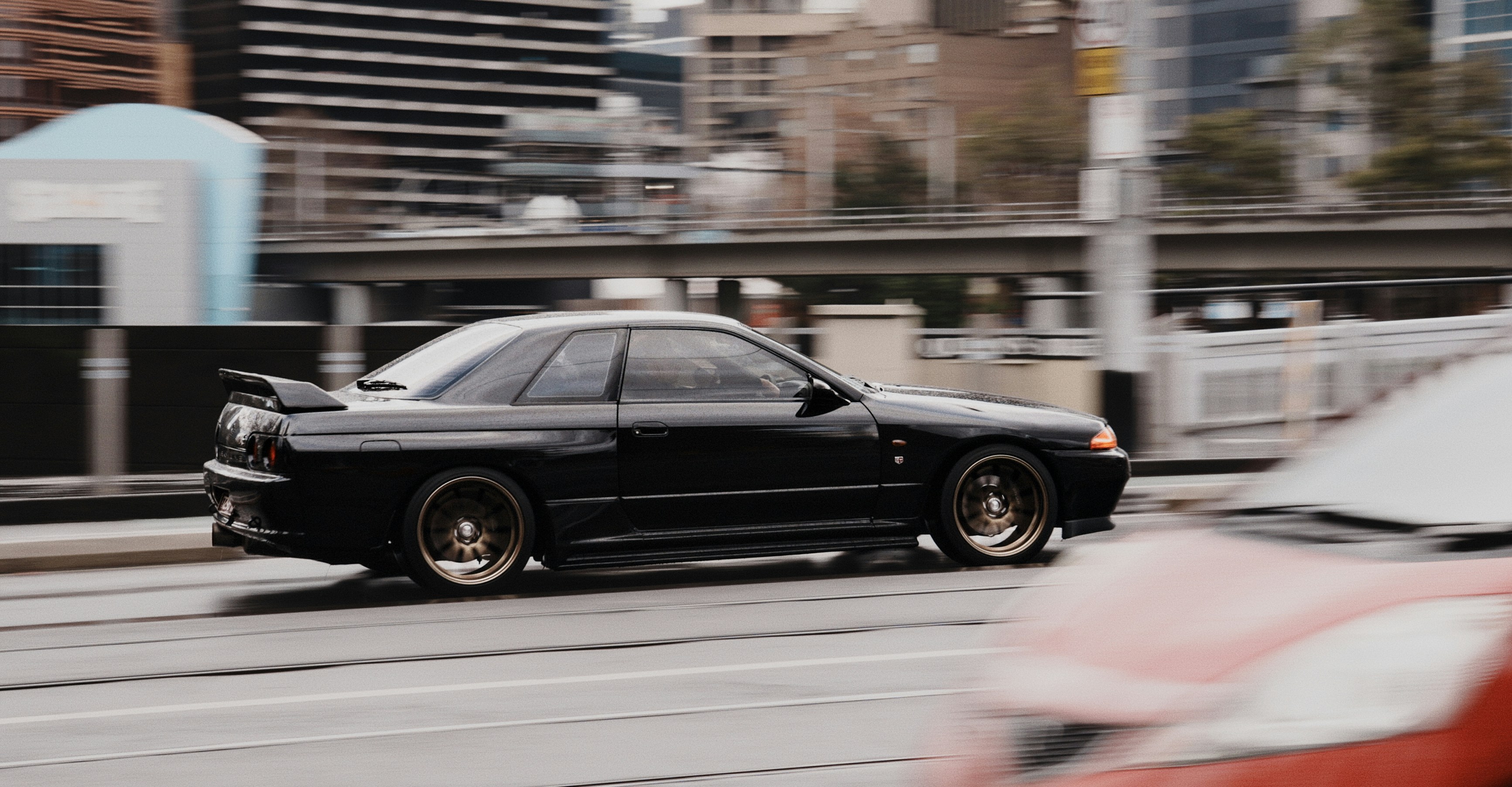 Schwarzer Sportwagen, der auf einer Straße in der Stadt fährt.