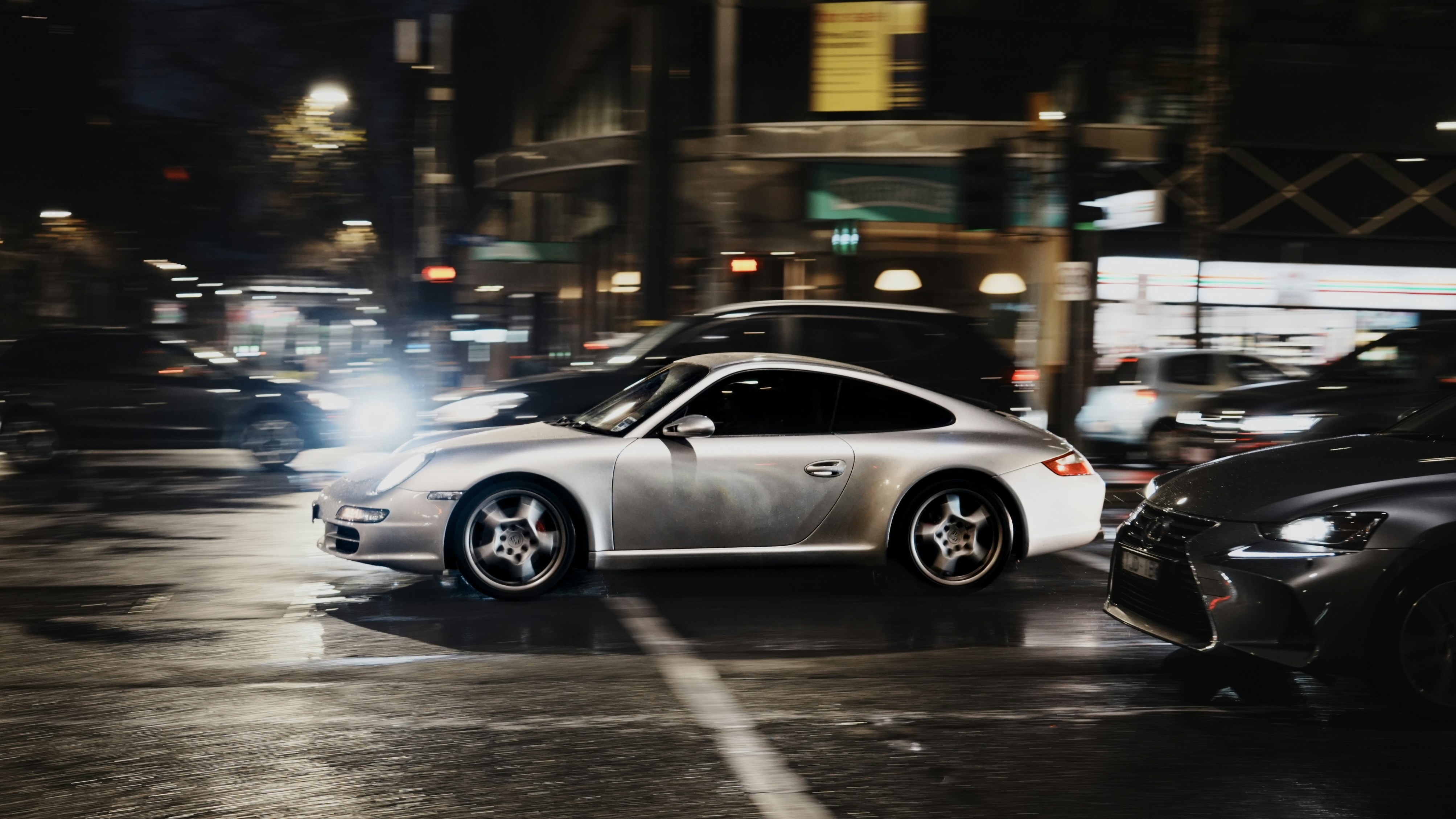 Silberner Porsche, der nachts durch die Straßen der Stadt fährt