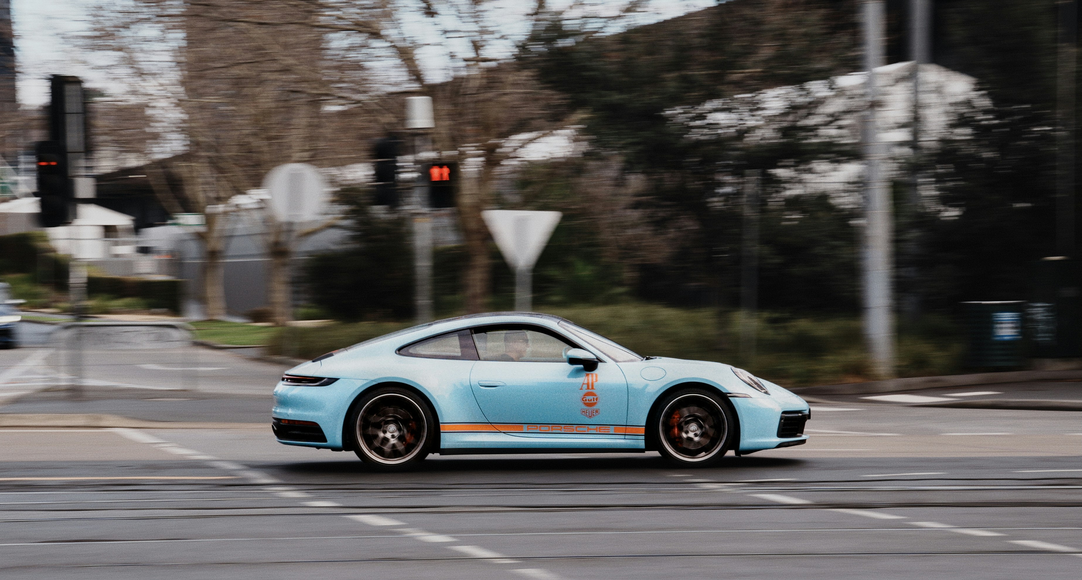 Hellblauer Porsche fährt über die Stadtkreuzung.