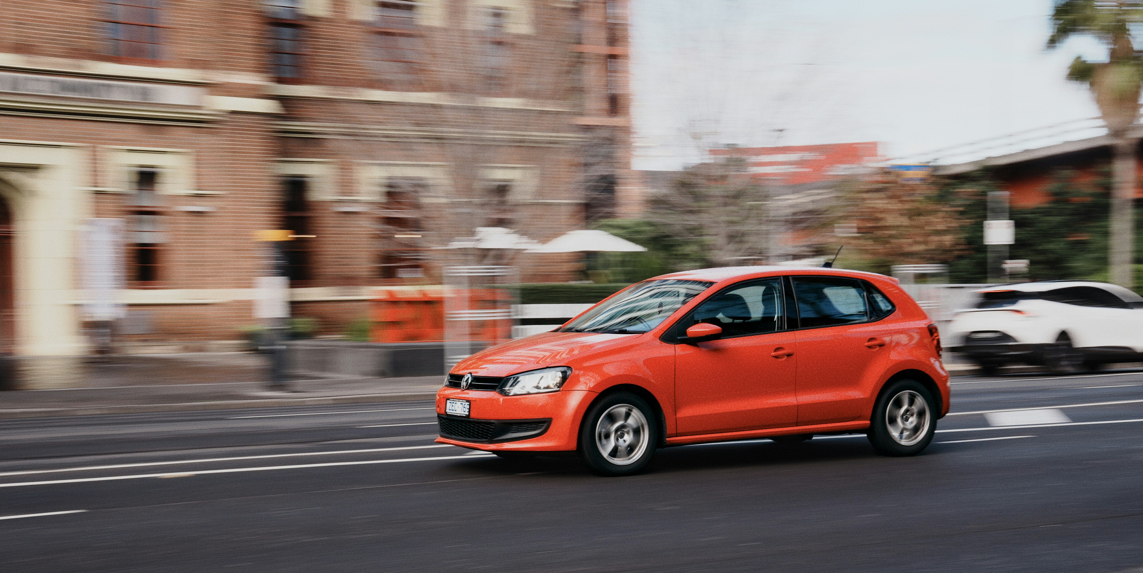 Orangefarbenes Auto, das auf einer Straße in der Stadt fährt