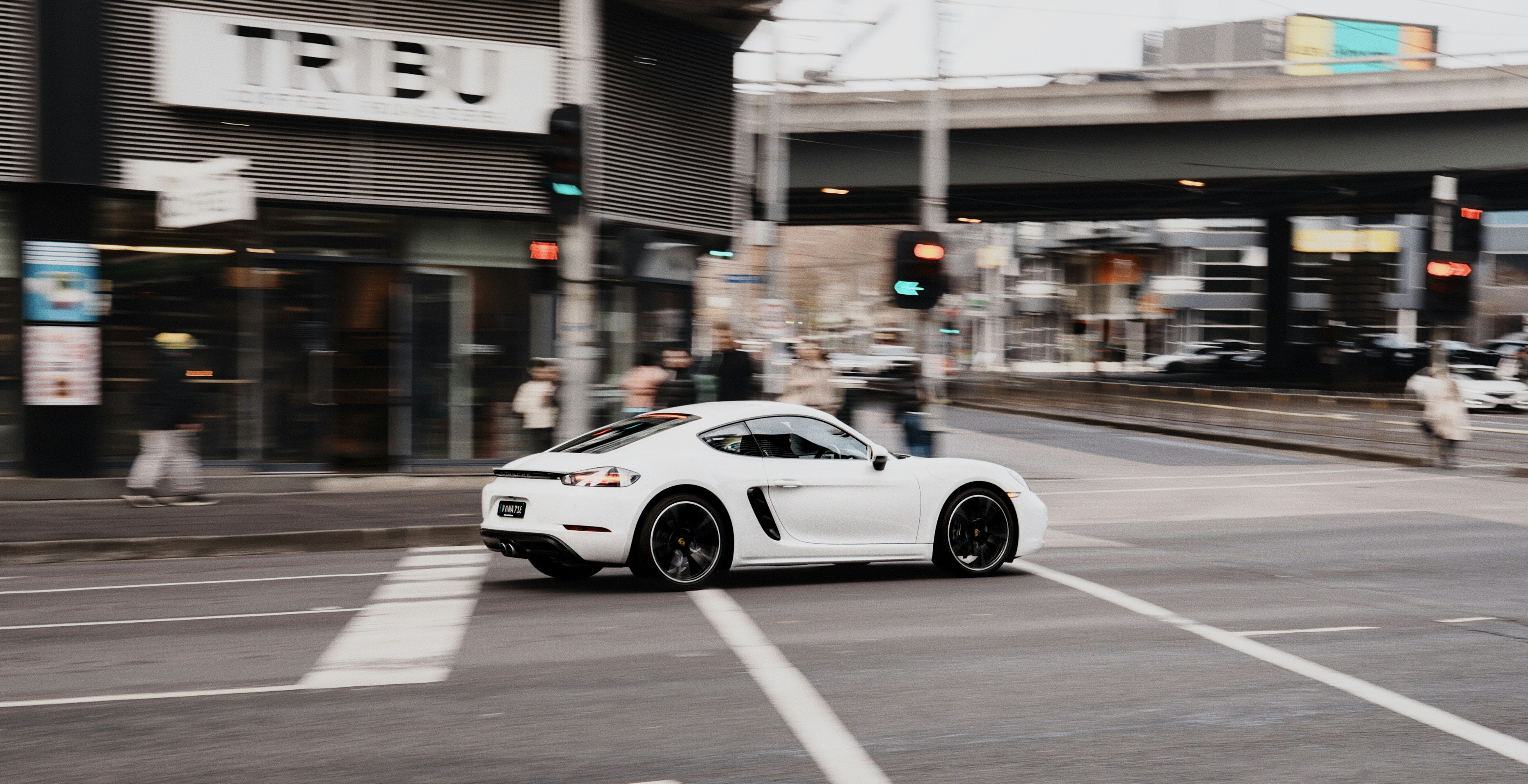 Weißer Sportwagen, der über die Kreuzung der Stadt fährt.