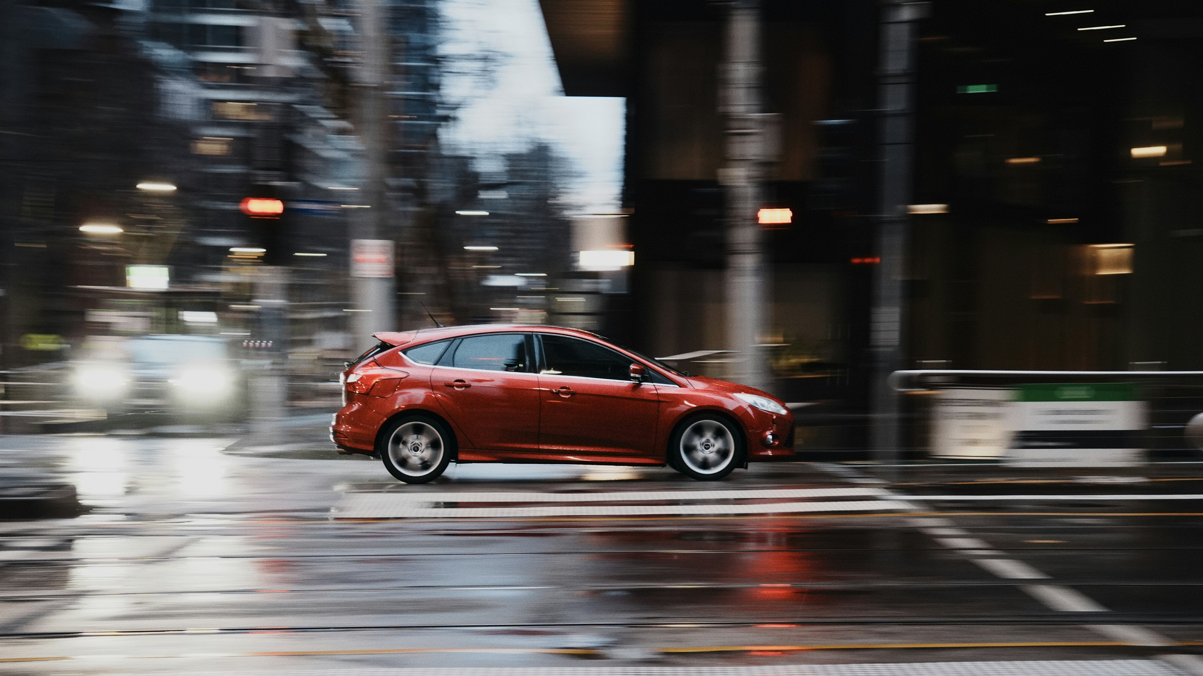 Rotes Auto, das nachts auf nasser Straße fährt