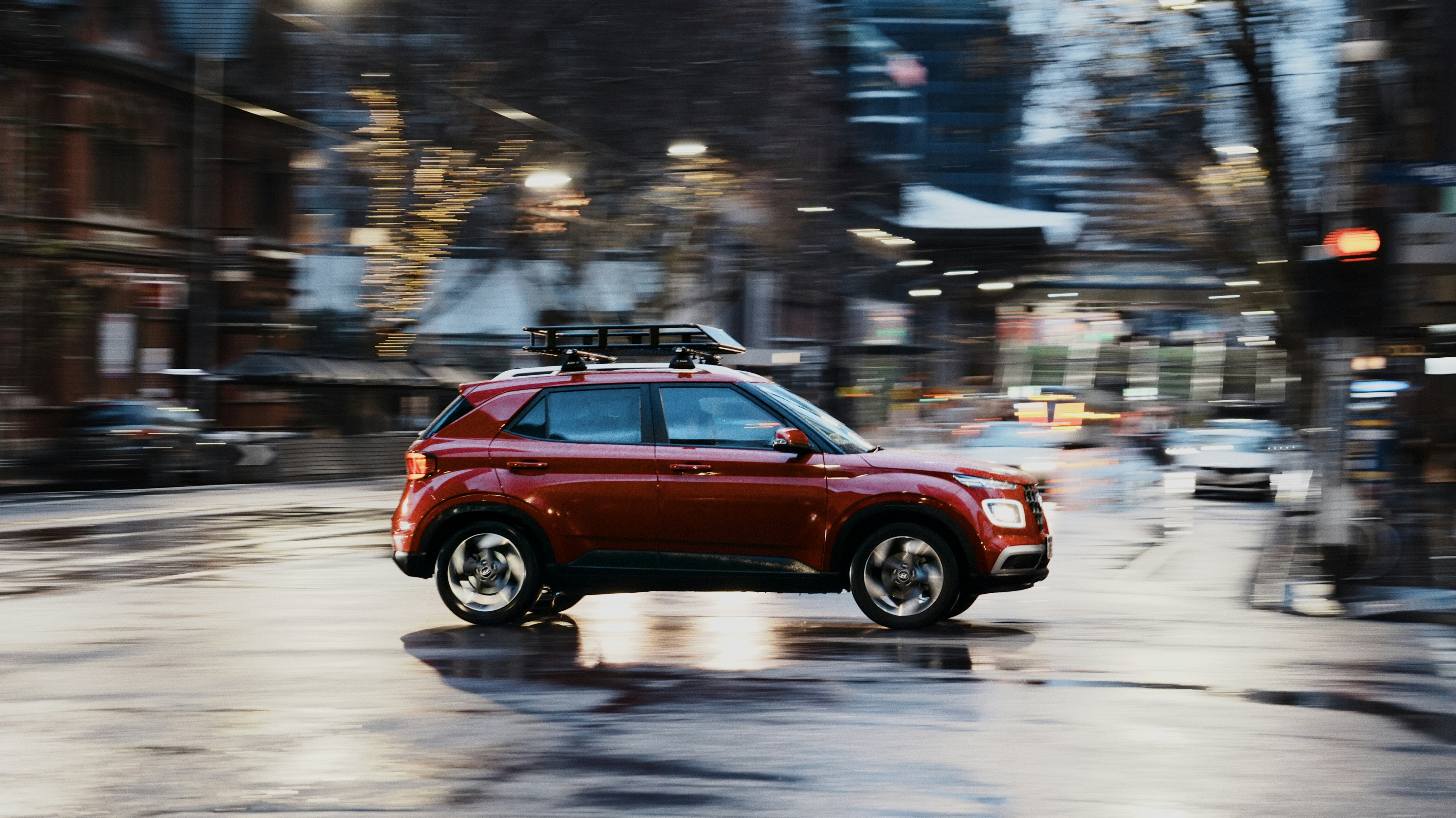 Rotes Auto, das auf einer nassen Straße fährt.