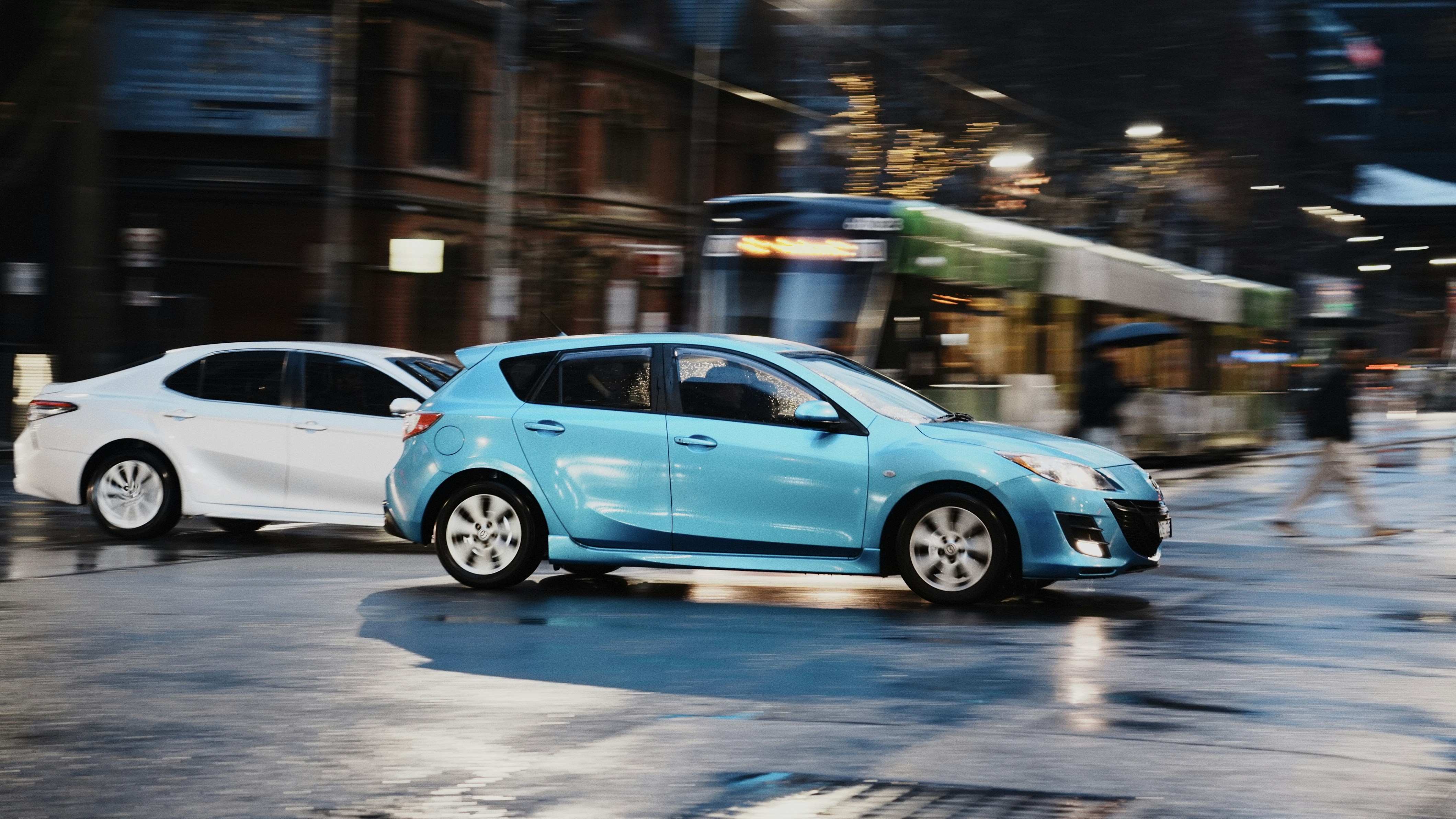 Blaues Auto, das nachts auf einer nassen Straße in der Stadt fährt