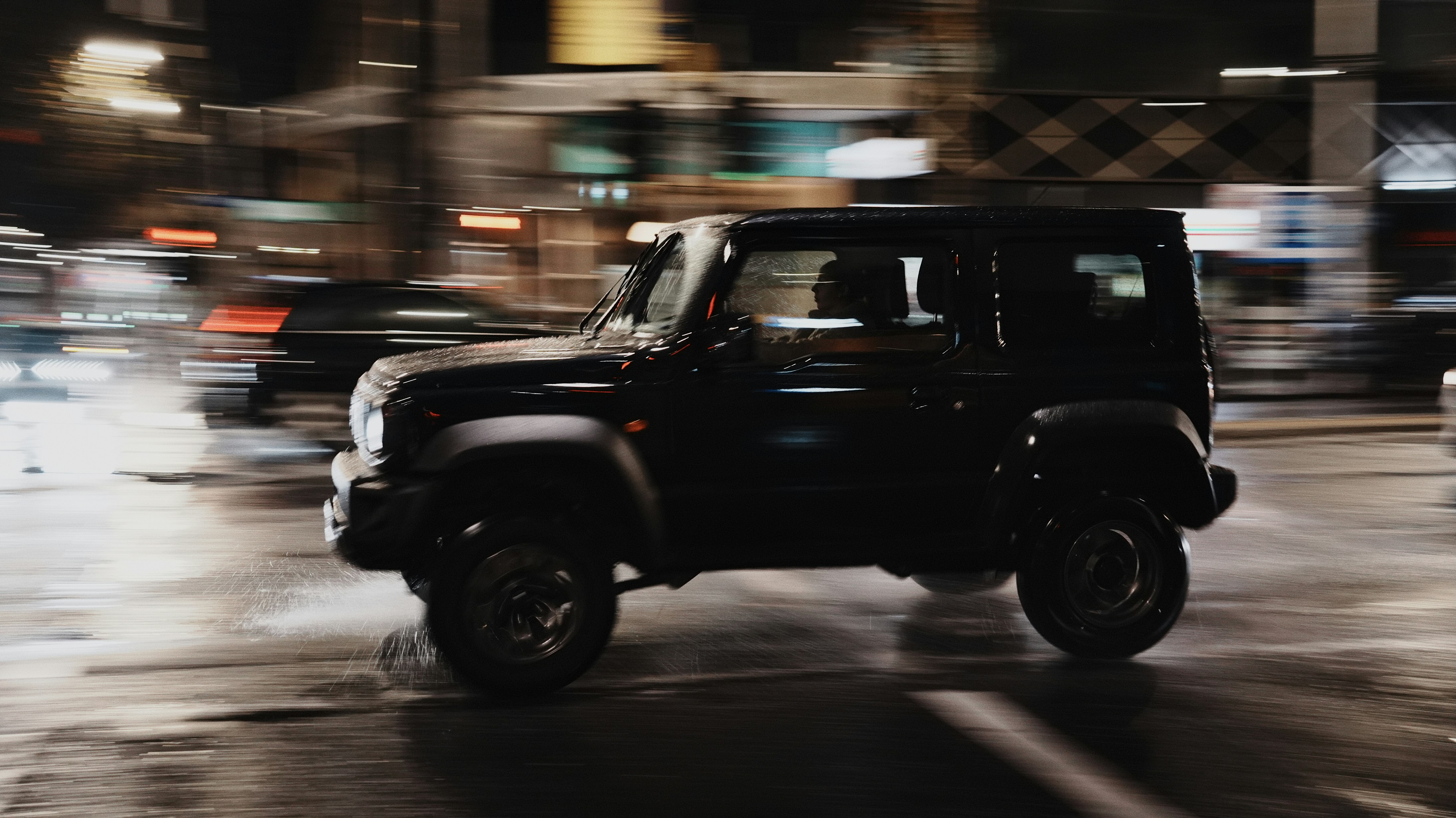 Schwarzer Jeep, der nachts durch eine verschwommene Straße fährt