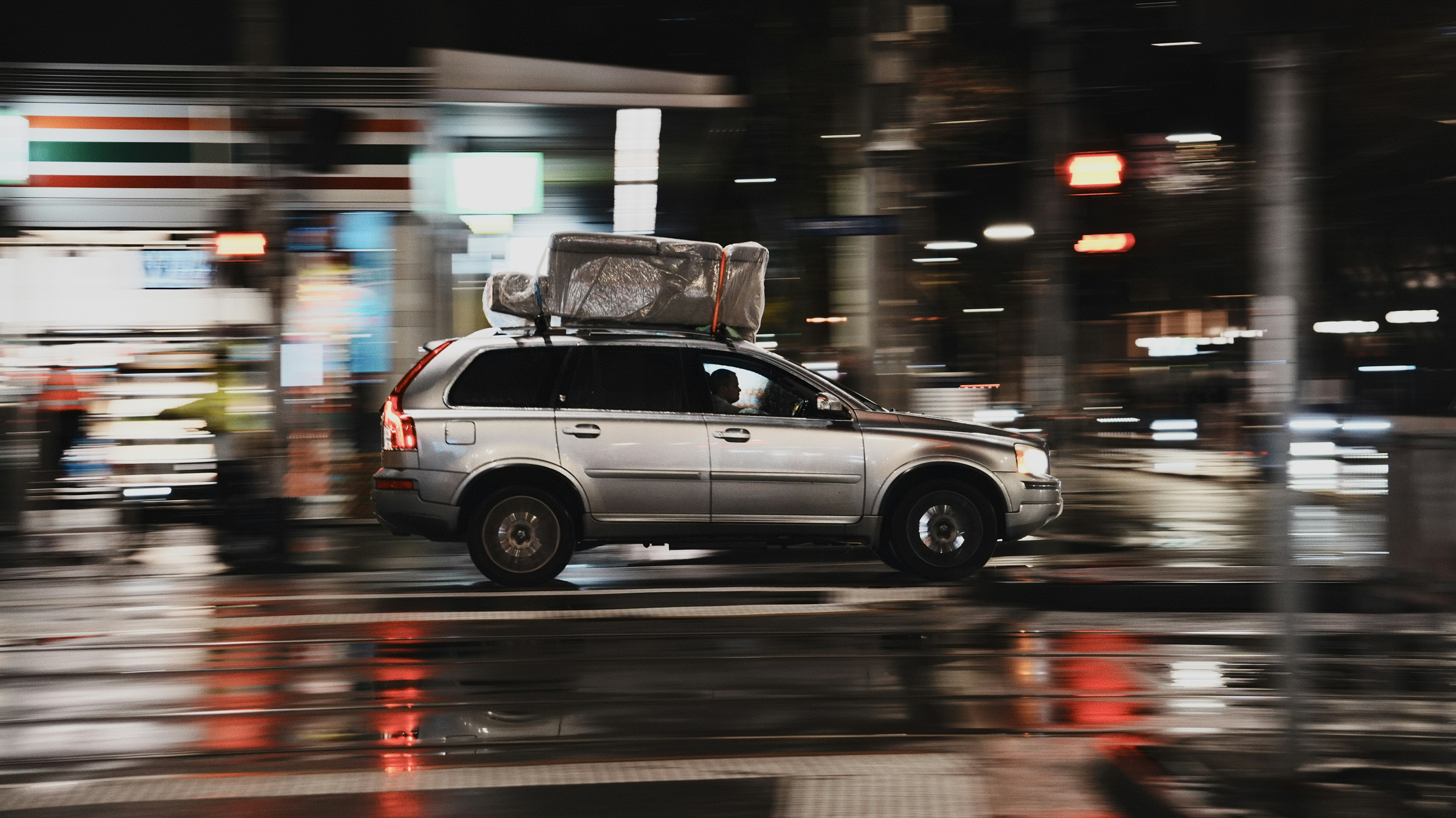 Silberner SUV mit Gepäck fährt nachts durch die Stadt