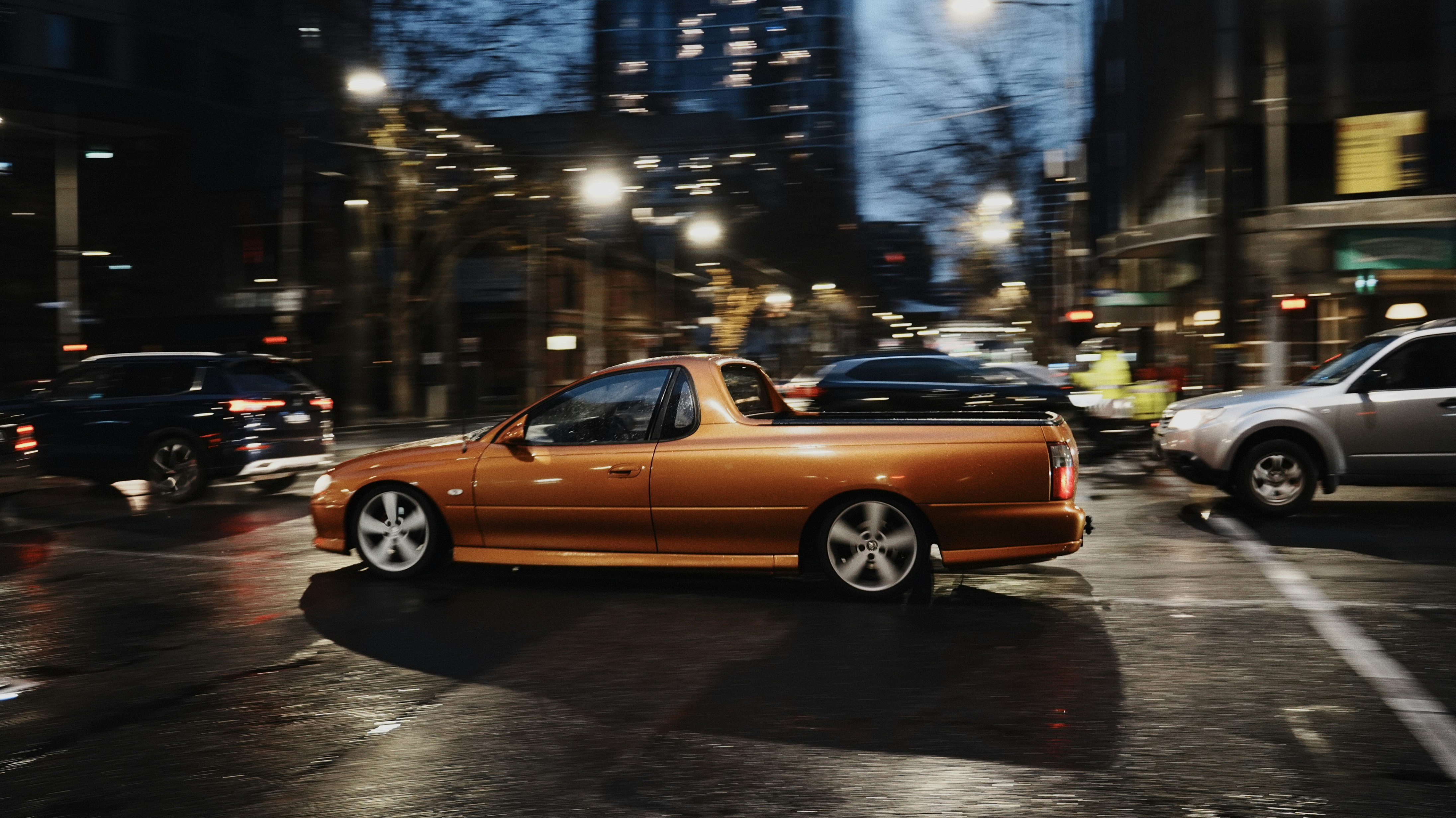 Orangefarbenes Auto, das nachts durch die Straßen der Stadt fährt.