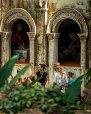 People gathered near ancient arched structures with statues.