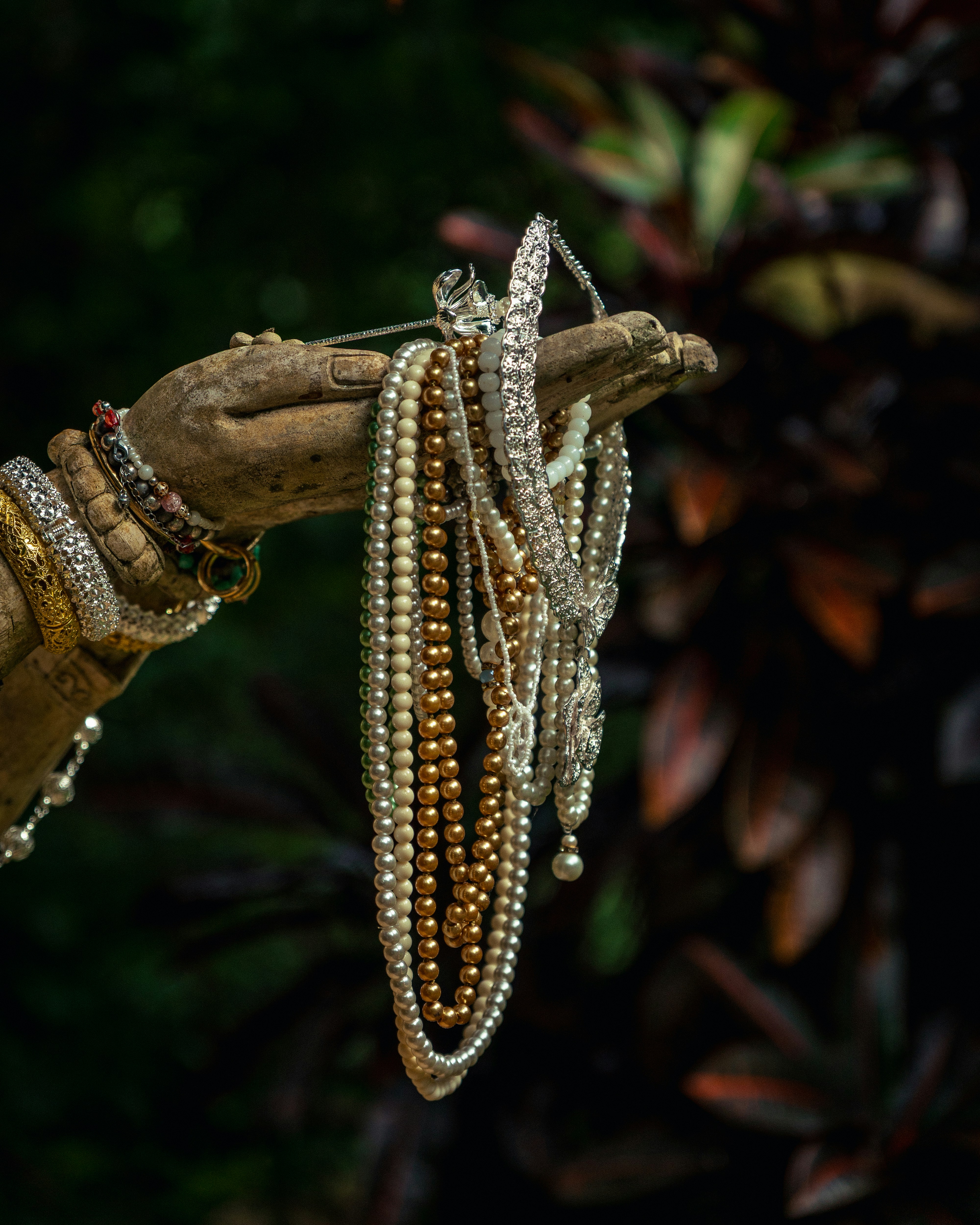 Mano della statua che tiene varie collane e bracciali di perle