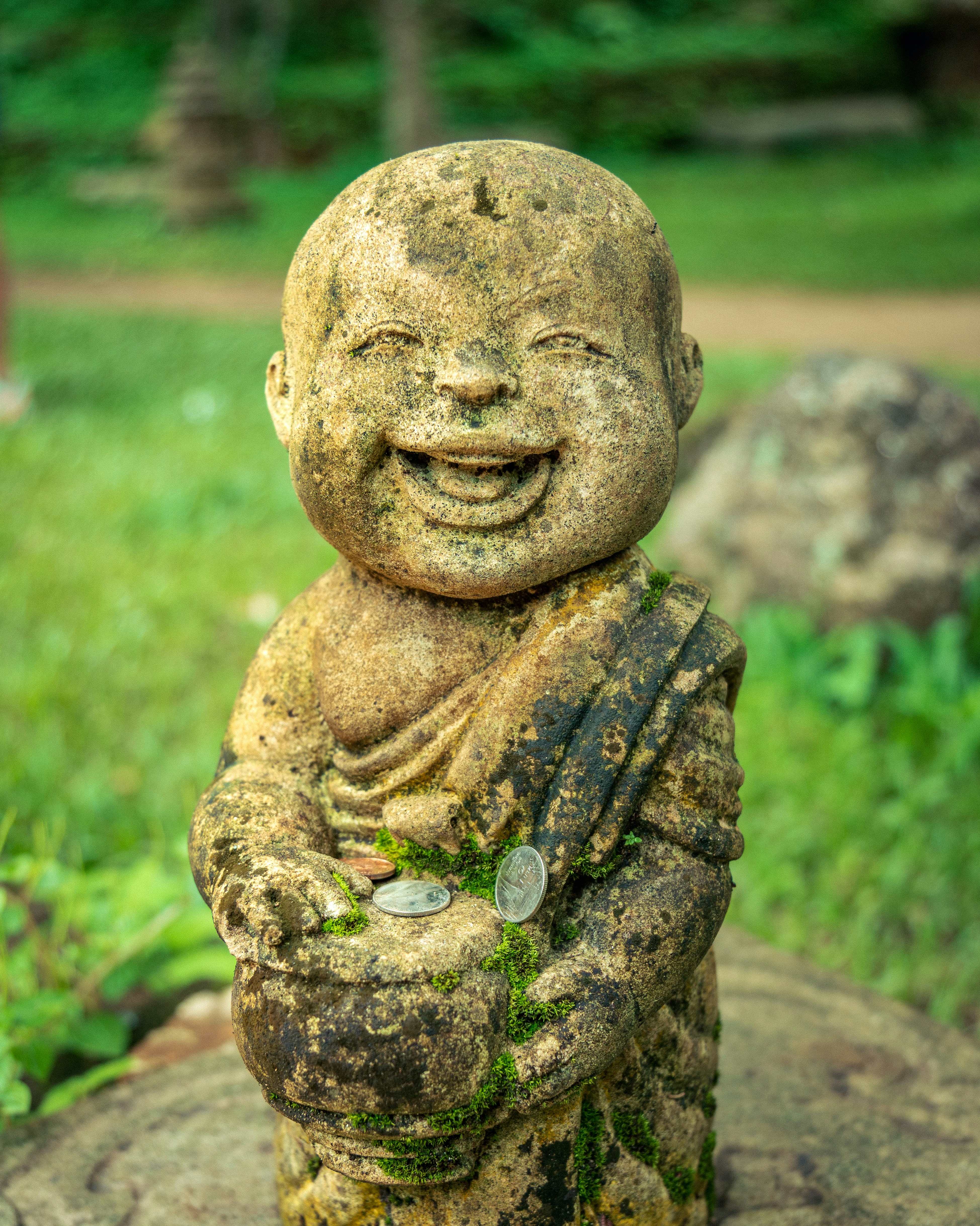 Stone statue of a smiling monk holding a bowl