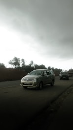 Cars driving on a road under a cloudy sky.