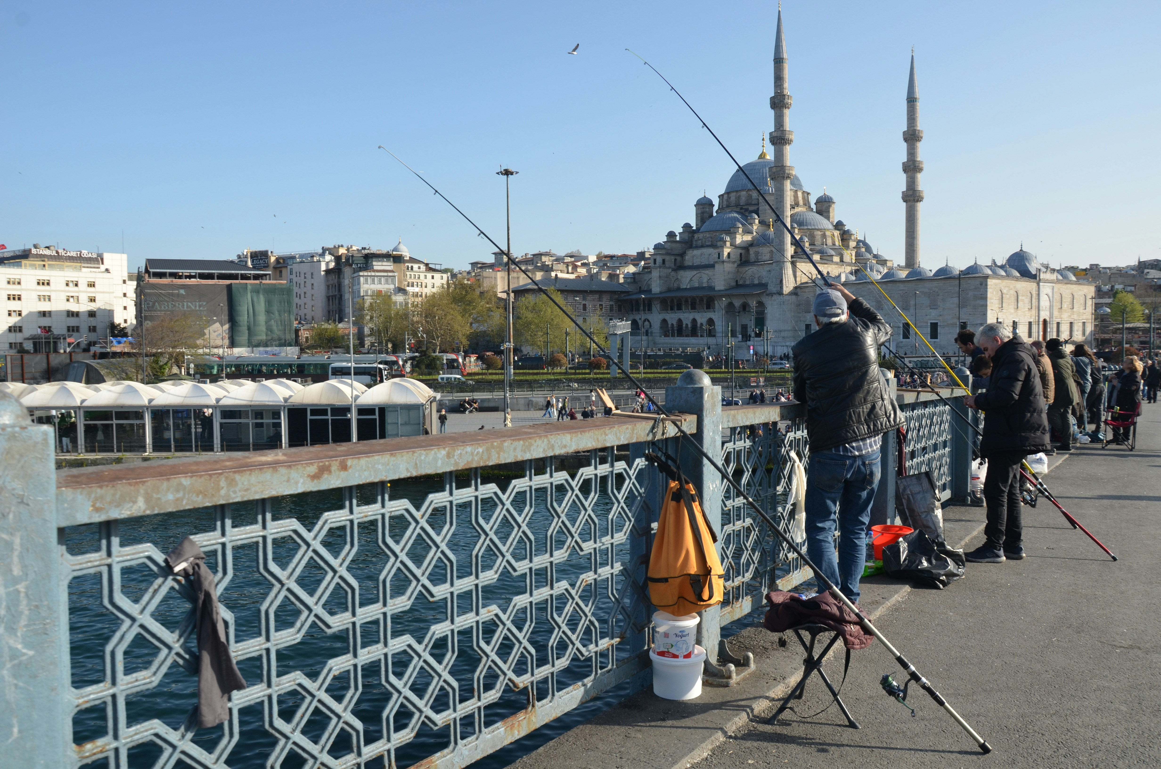 People fishing on a bridge with a mosque in background