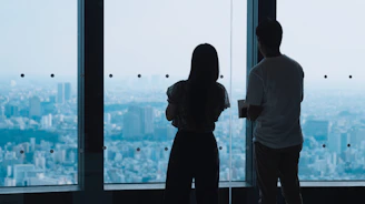 Two people looking out a window at city