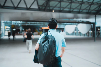 Man with backpack walks through modern building.