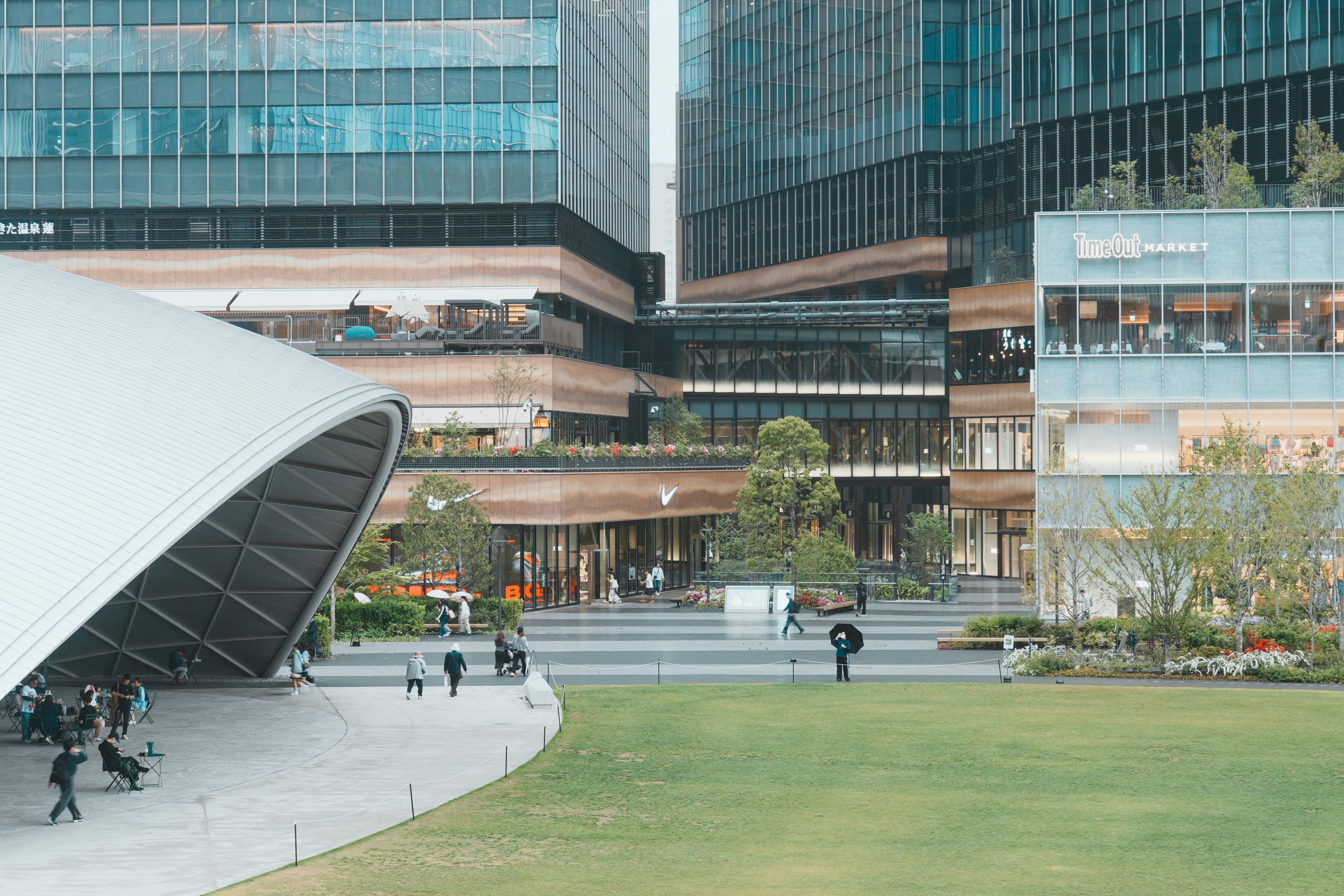 大きな湾曲した屋根と緑豊かな公園を備えたモダンな建物。