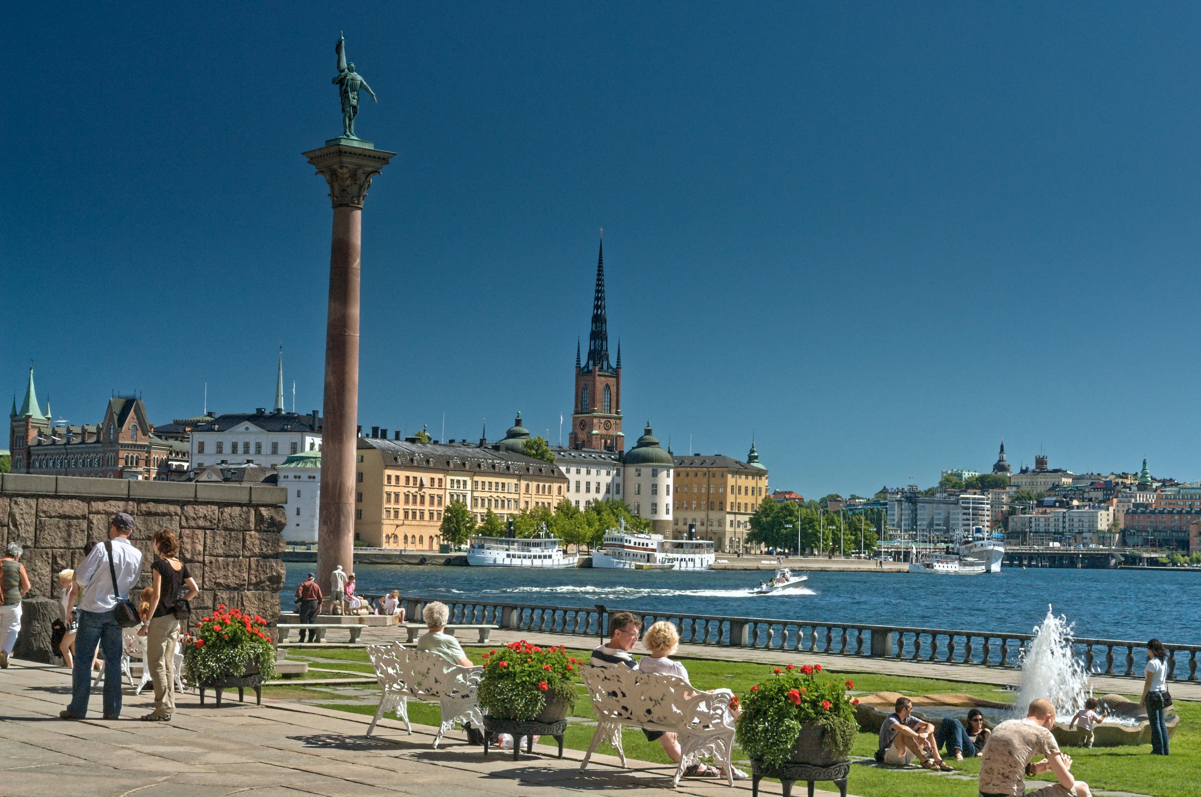 People relax in a park with stockholm cityscape and water.
