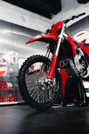 Red dirt bike parked in a showroom.