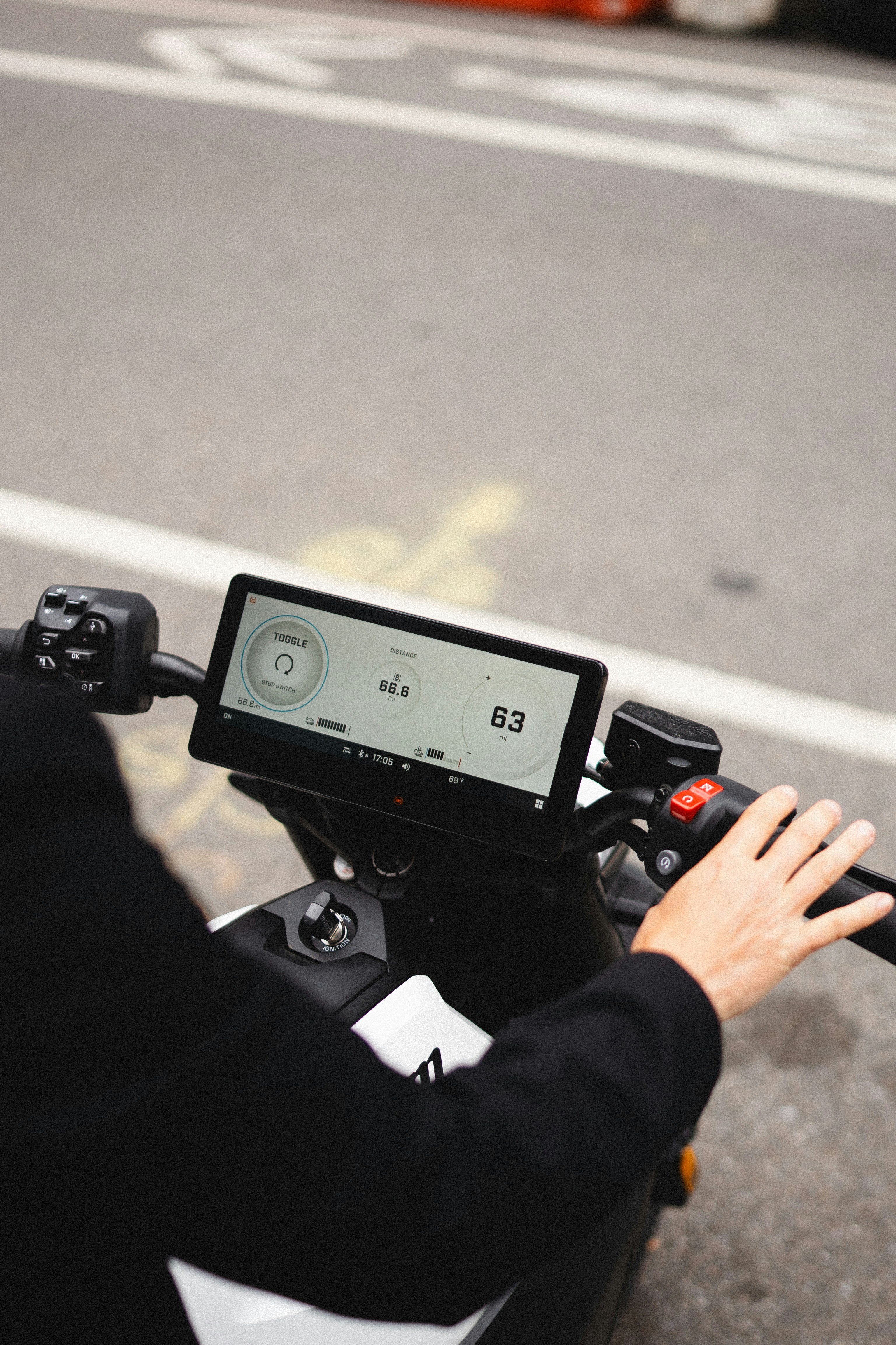 Rider's hands on a modern electric scooter dashboard.