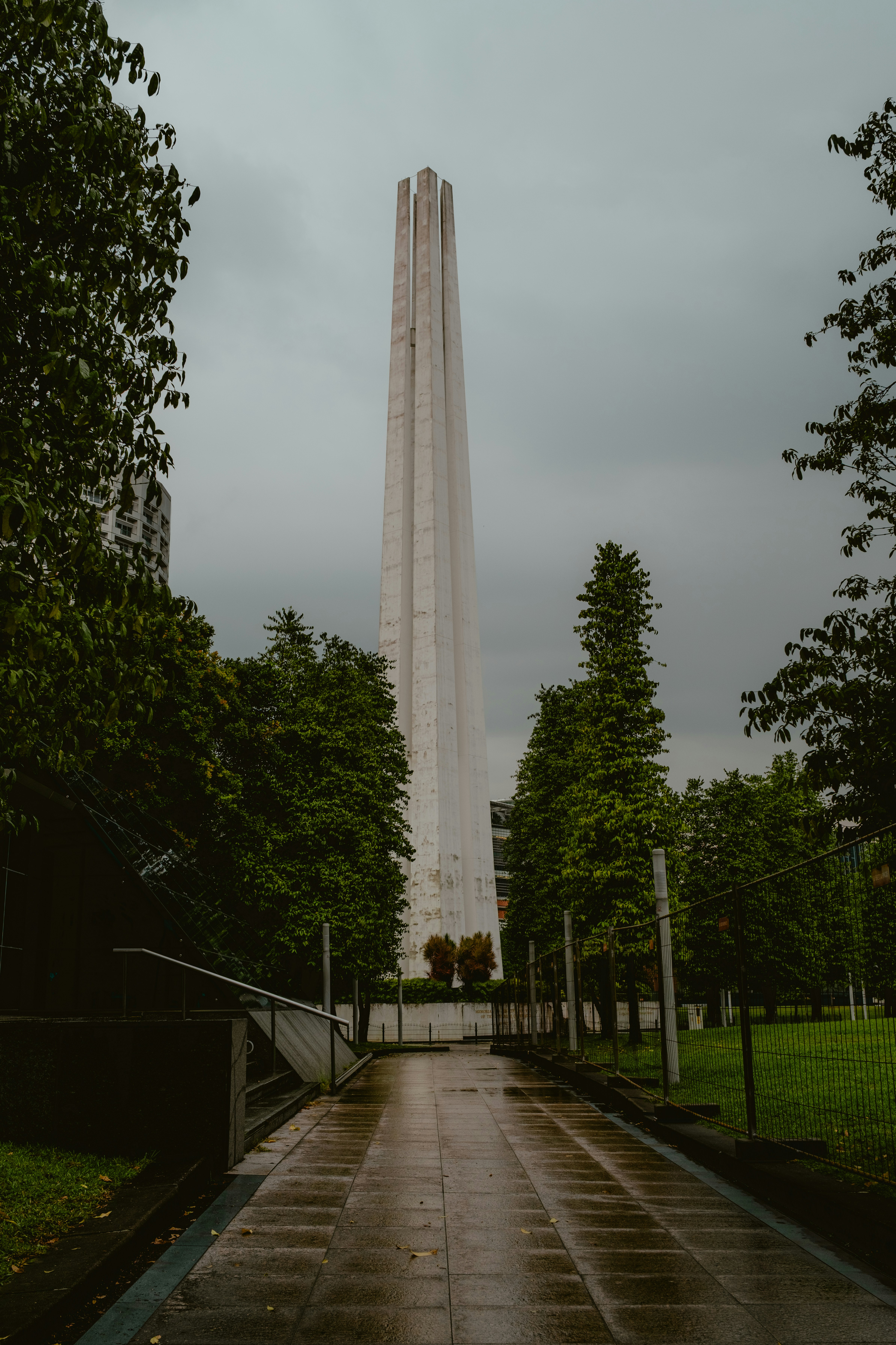 Tall white monument with trees and cloudy sky