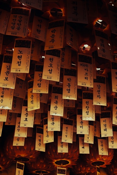 Many hanging korean prayer tags illuminated by warm light.