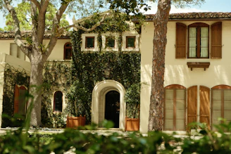 Large stucco house with green ivy and wooden shutters.