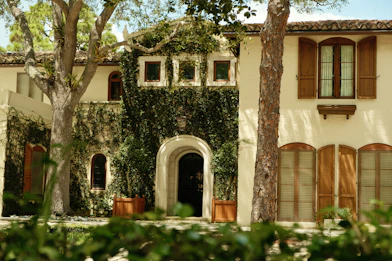 Large stucco house with green ivy and wooden shutters.