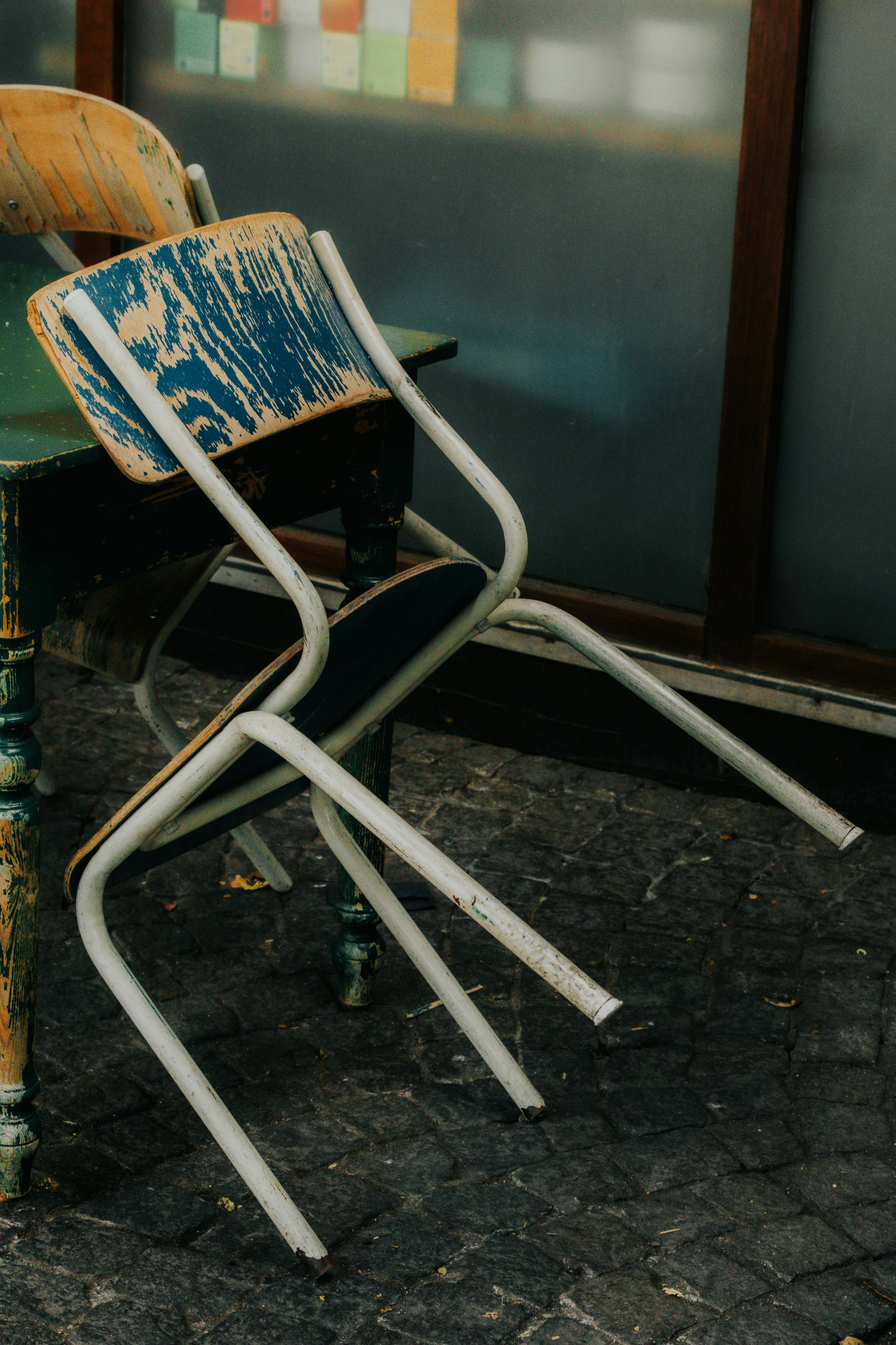 Two old chairs stacked messily on pavement.