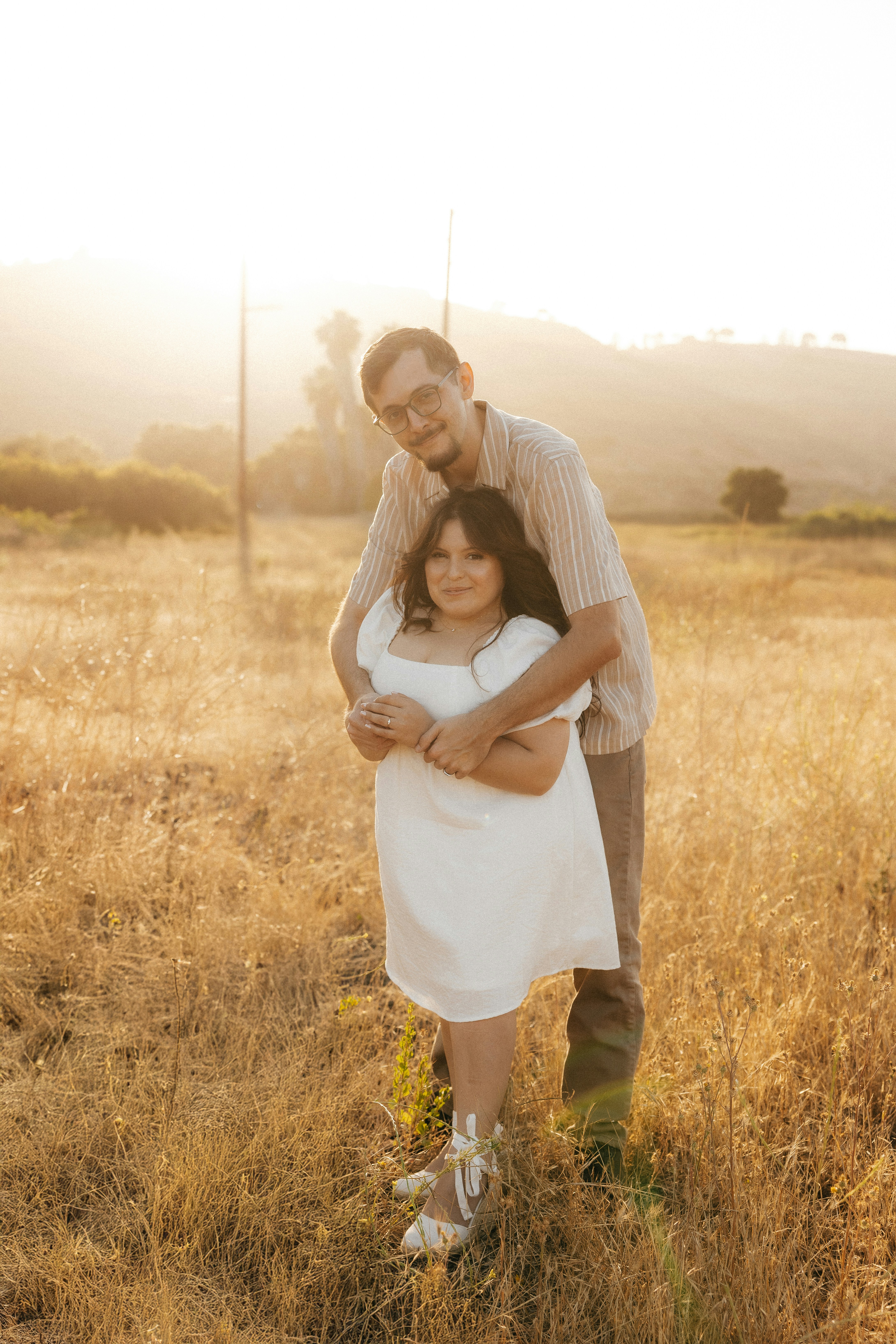 Couple embracing in a sunlit field at sunset