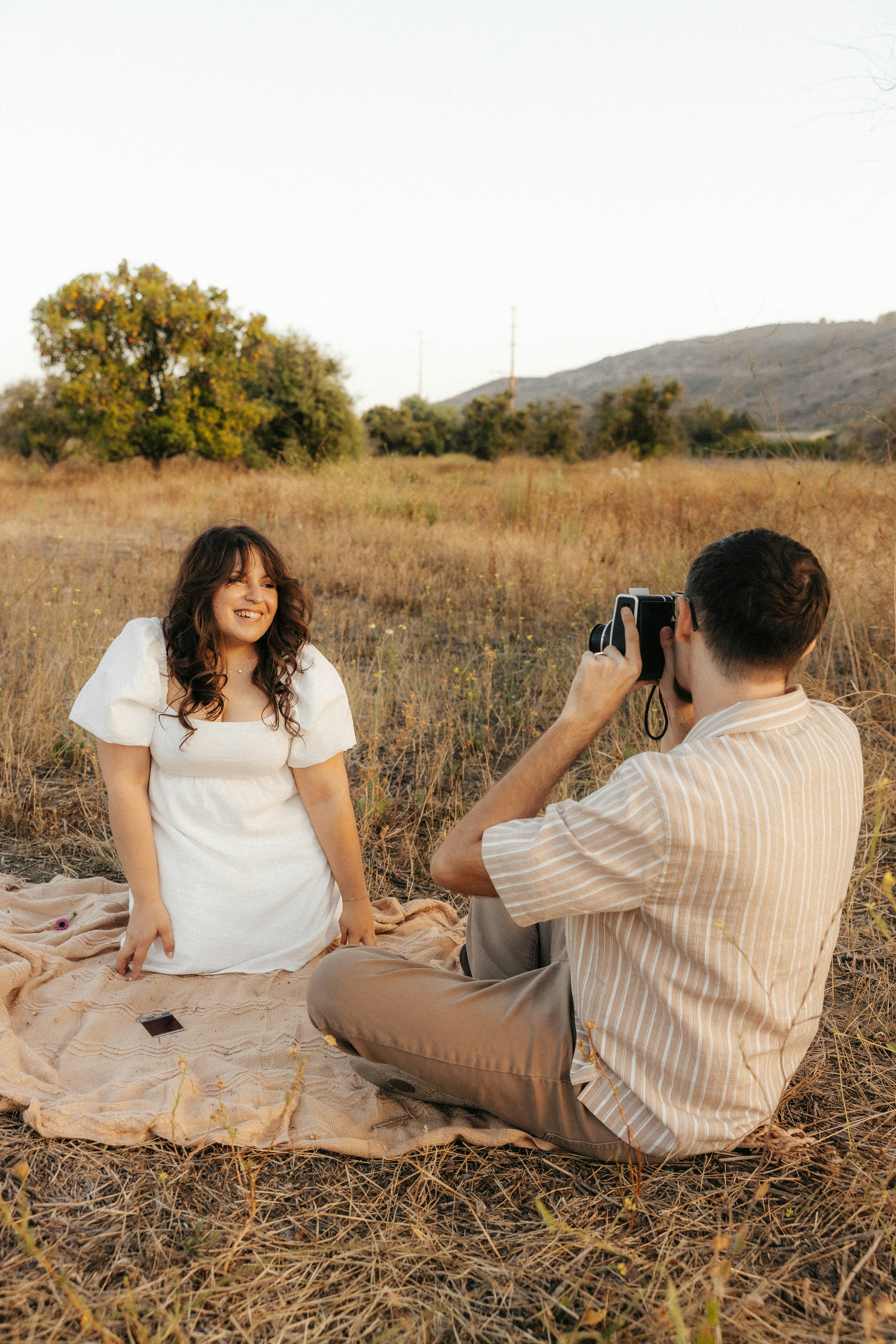 Man taking picture of woman in field
