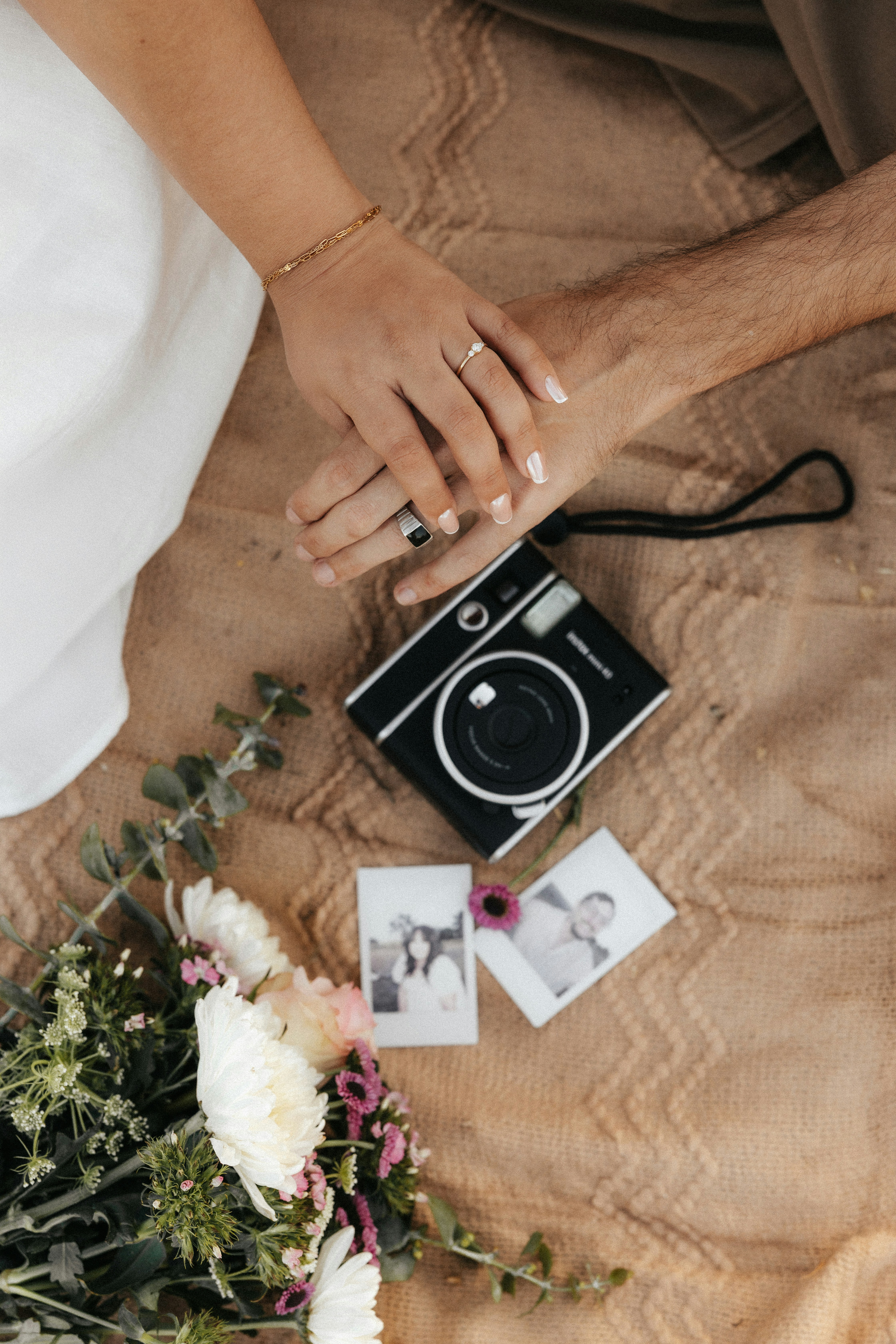 Couple holding hands with instant camera and flowers