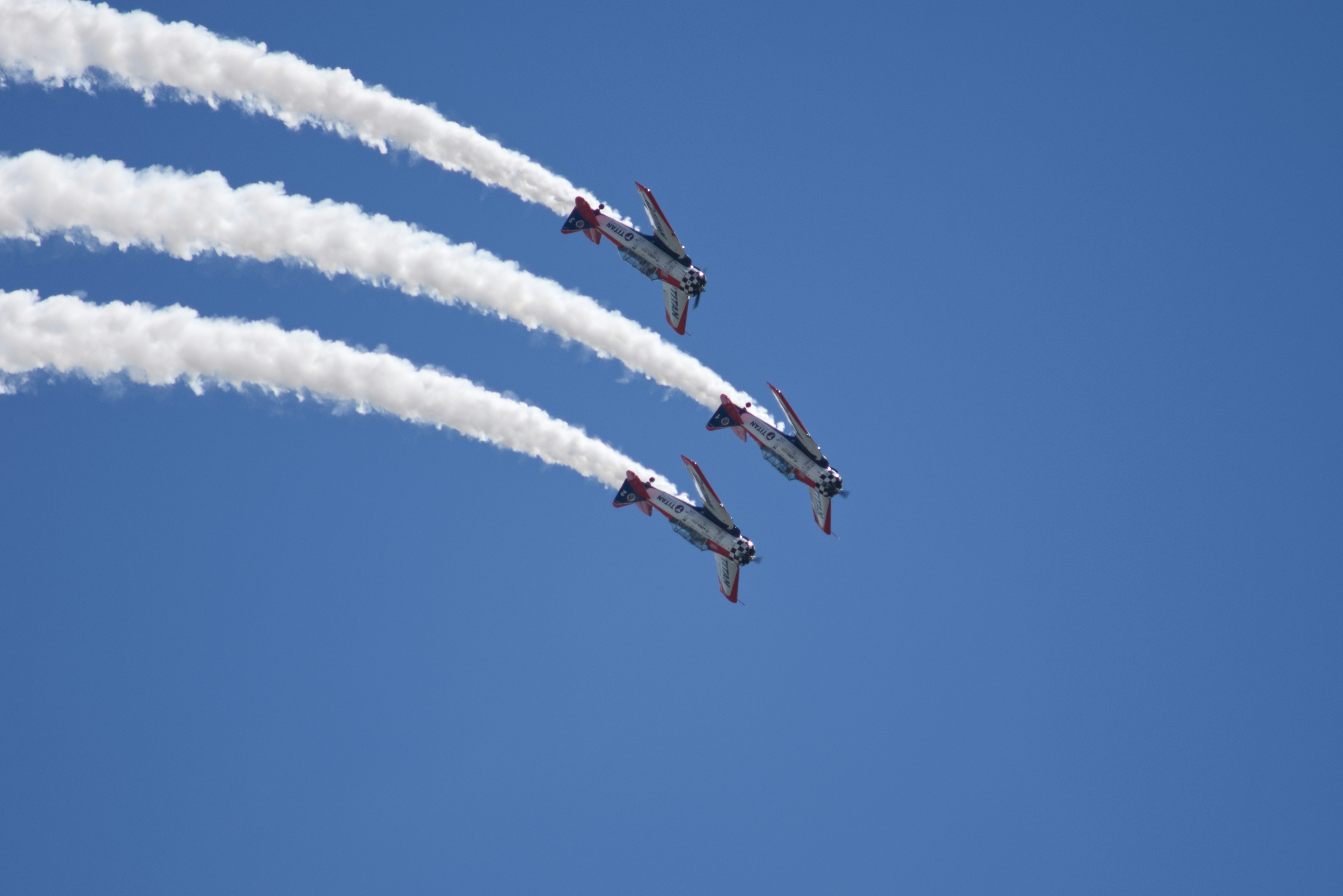 Three planes fly in formation leaving smoke trails.