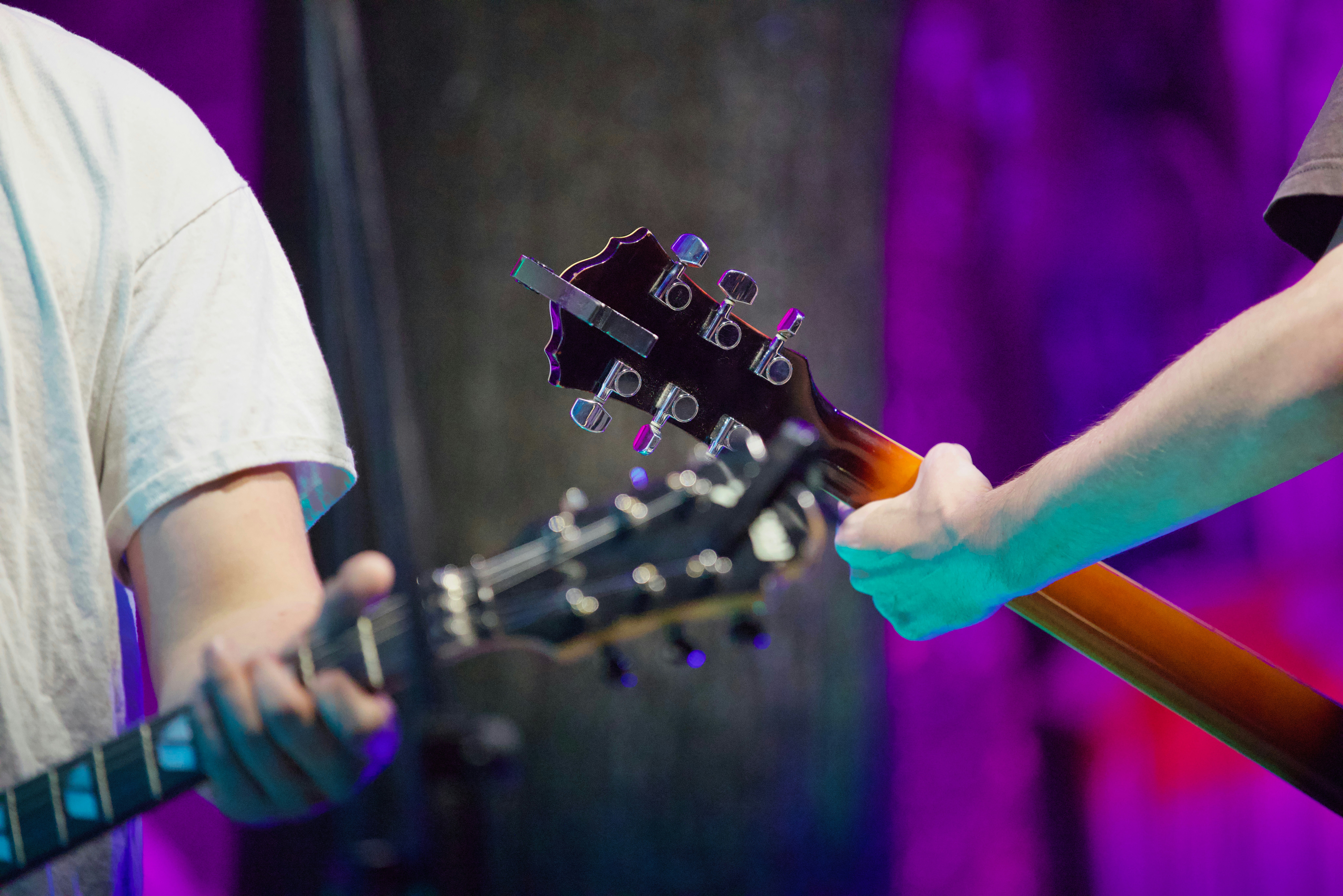 Músicos sosteniendo guitarras con fondo colorido