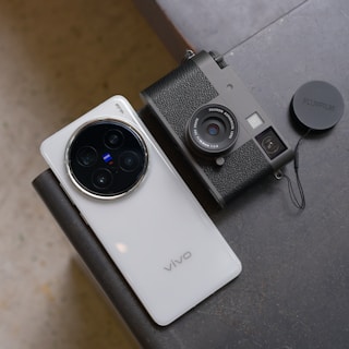Smartphone and vintage camera resting on a surface