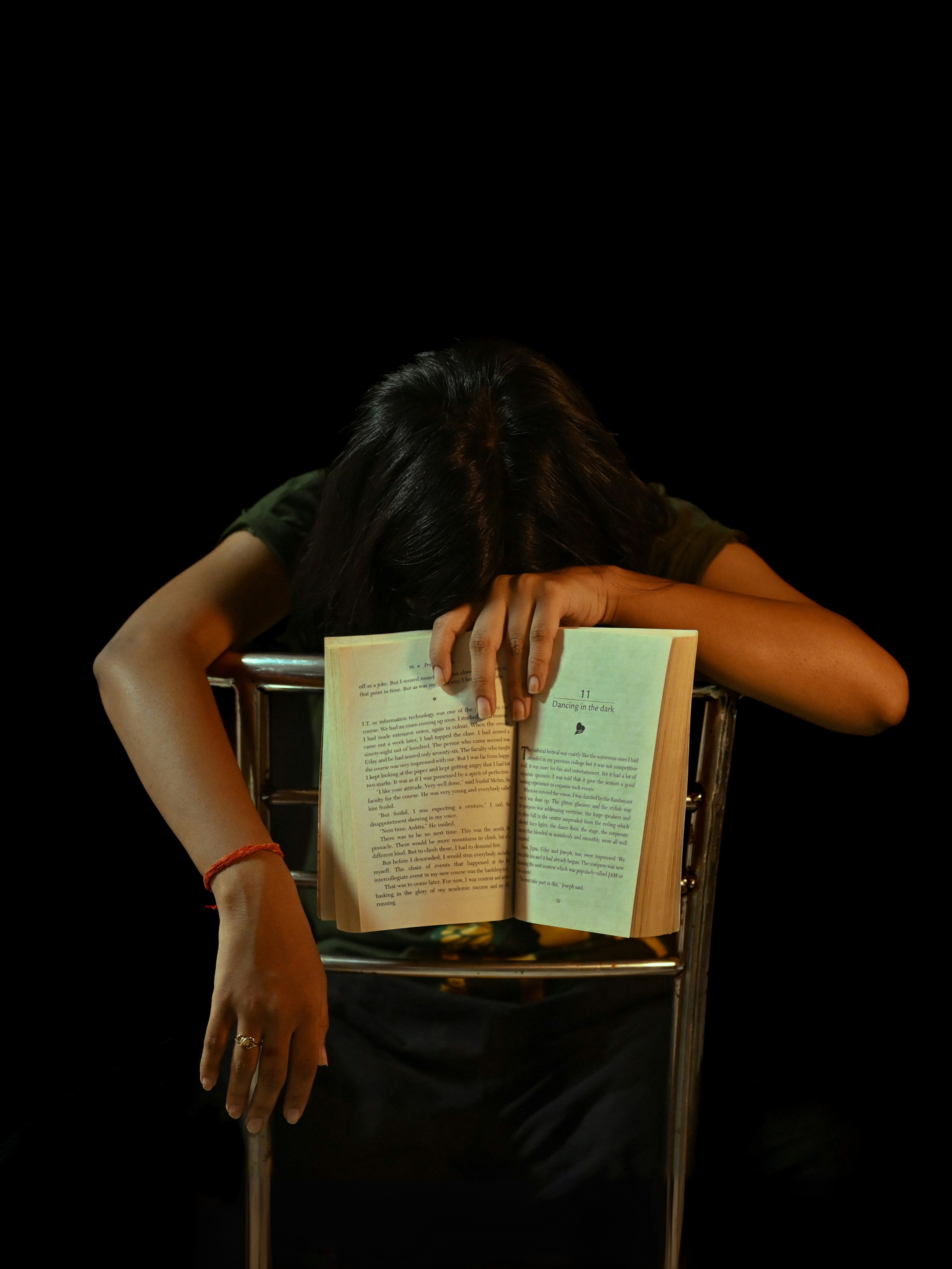 Person resting head on open book
