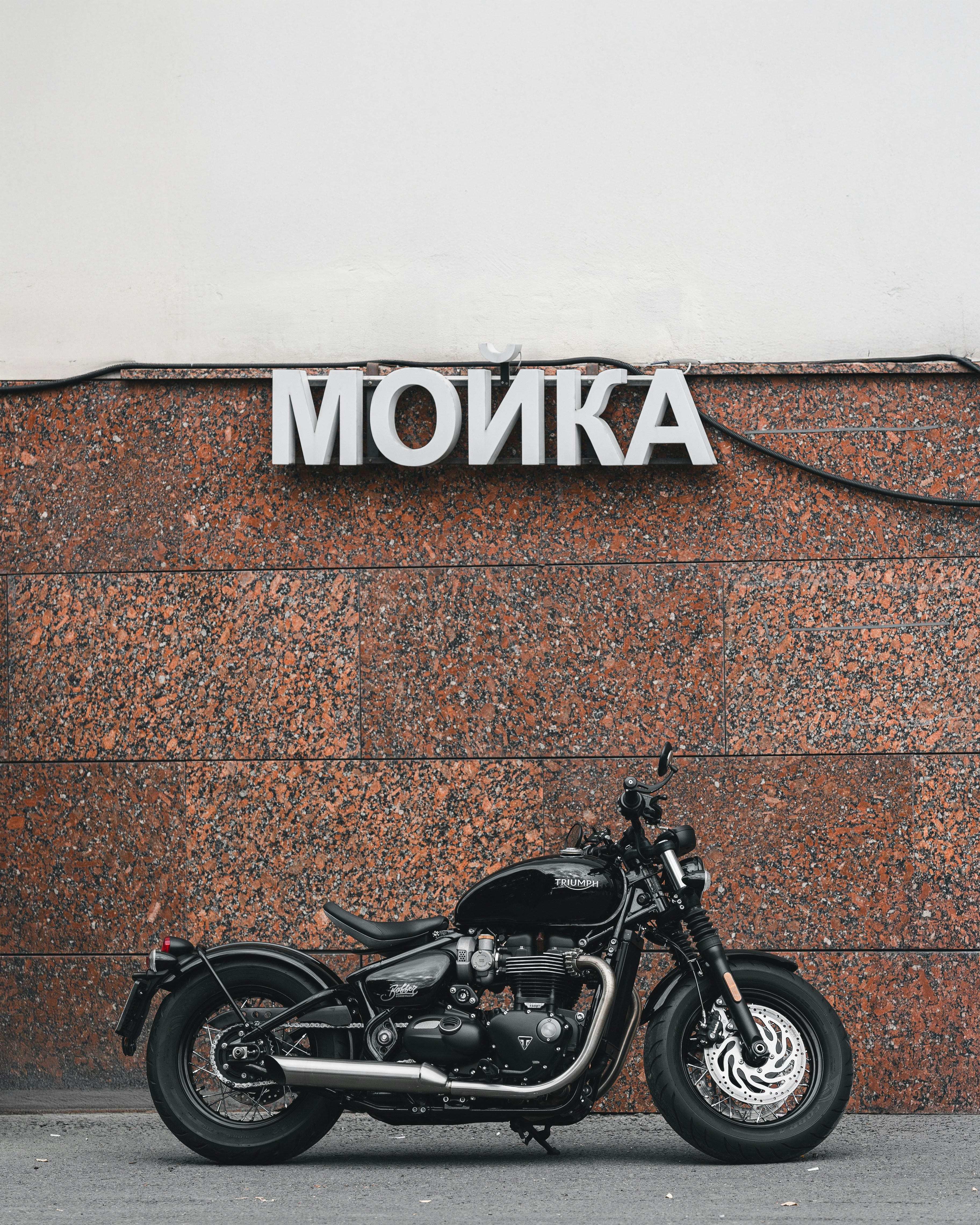 Black motorcycle parked against a granite wall
