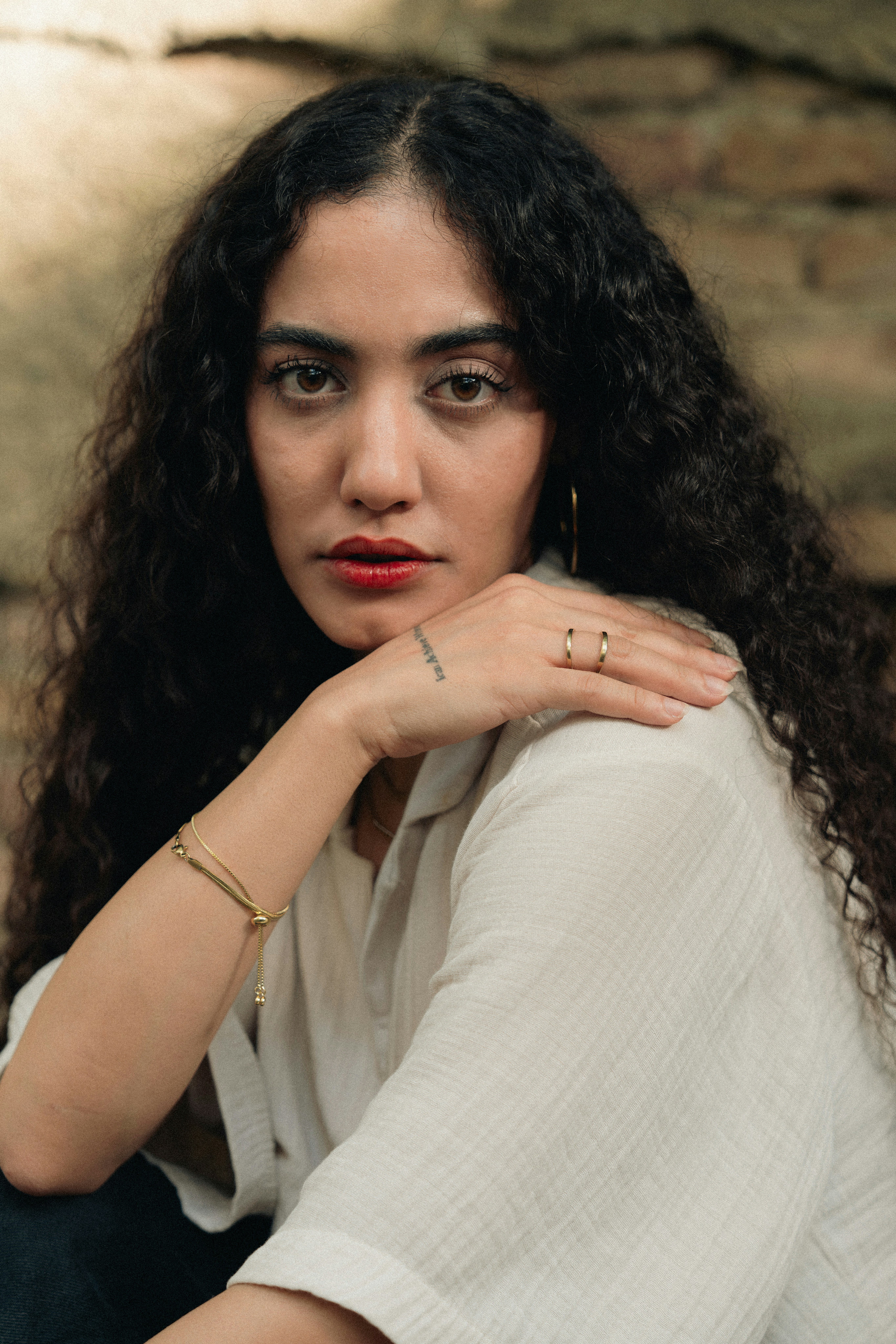 Woman with curly hair and red lipstick looking at the camera.
