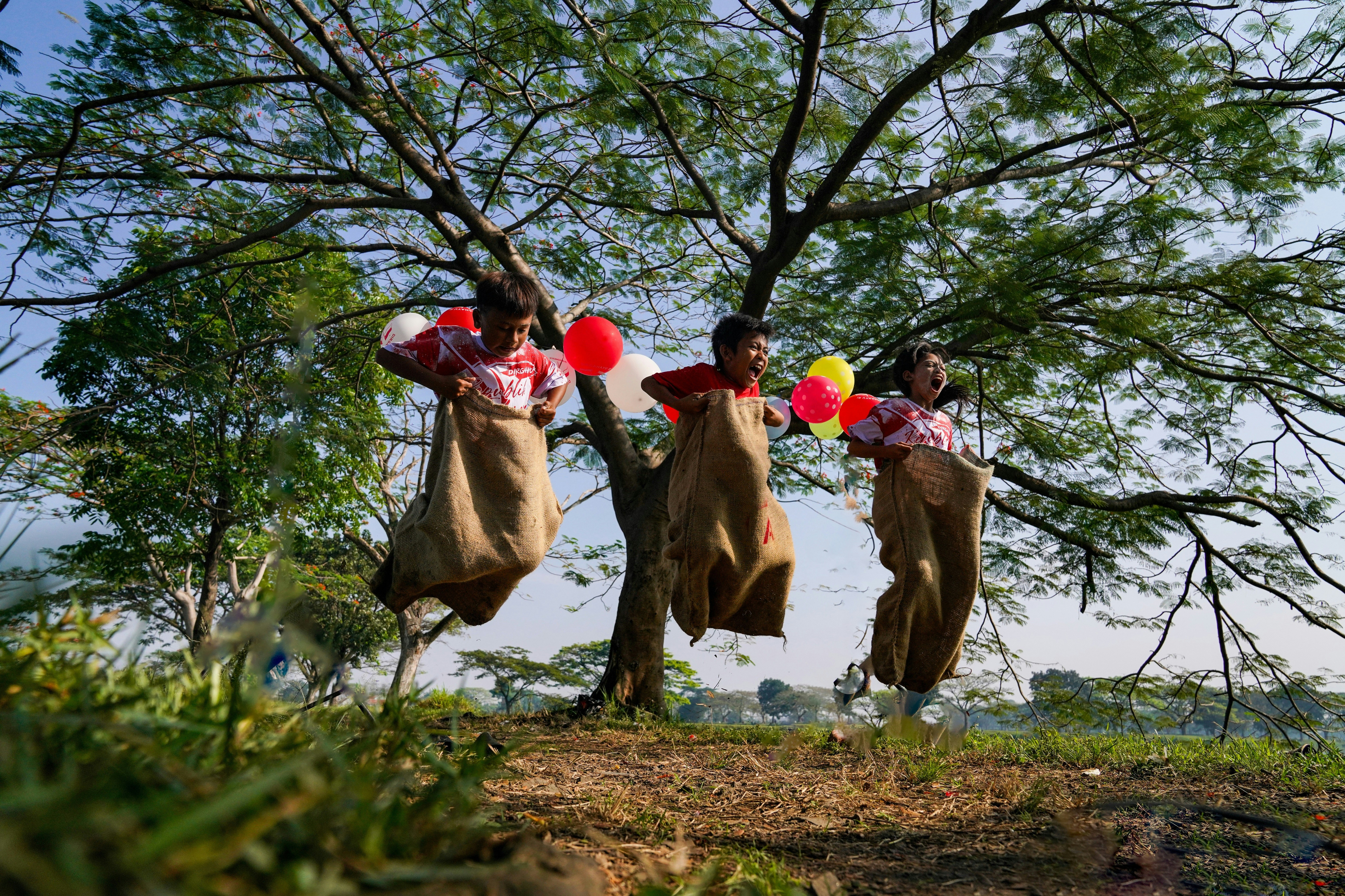 Children jumping in sacks during a game outdoors