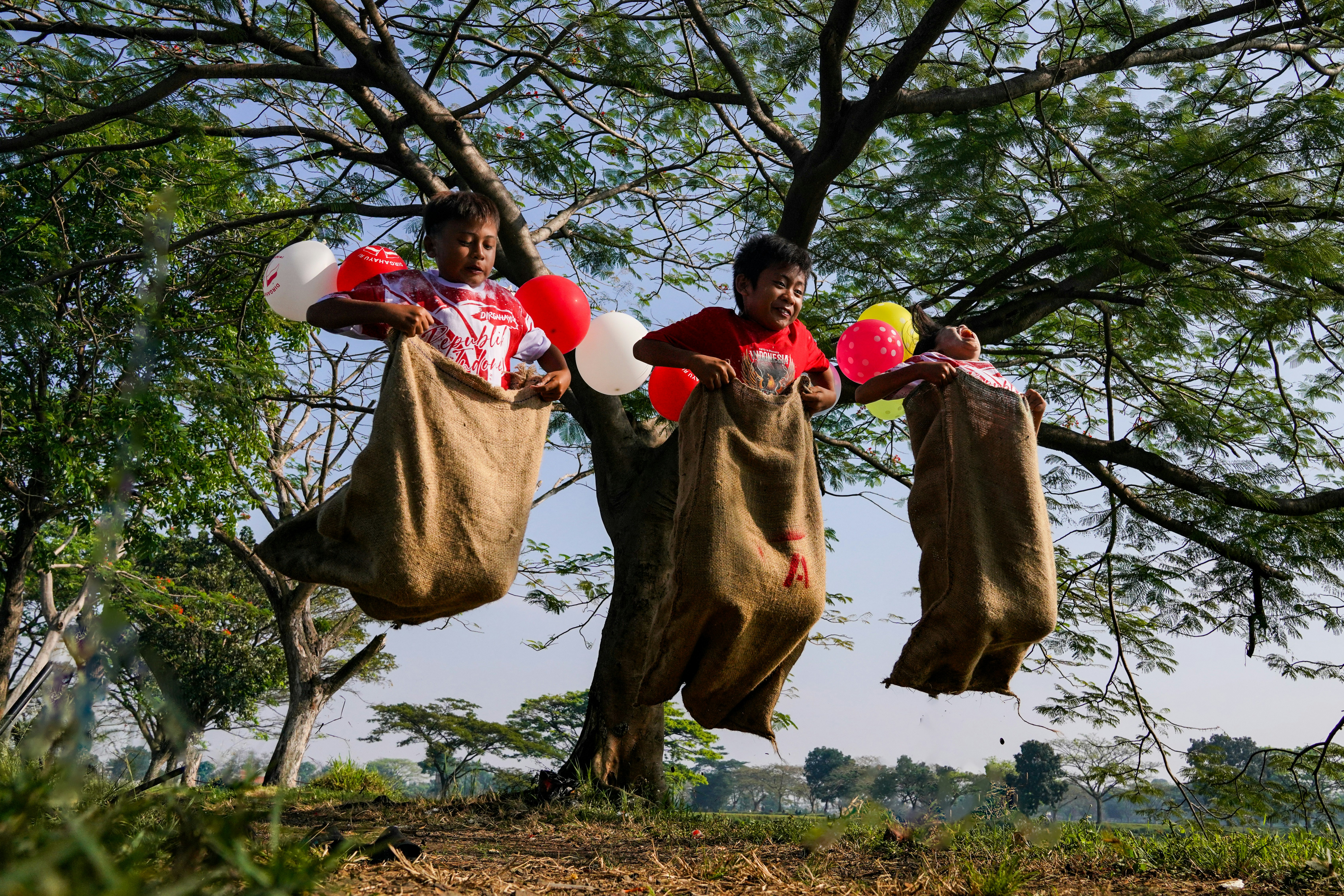 Two boys jumping in sacks with balloons