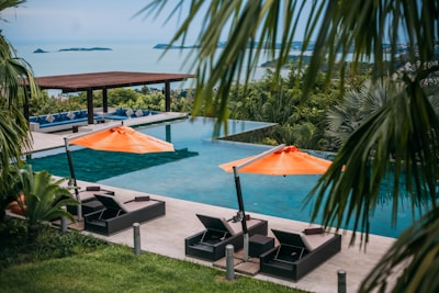 Infinity pool with lounge chairs and umbrellas overlooking ocean.