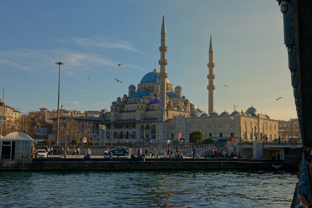 Grand mosque with blue domes and minarets by water.