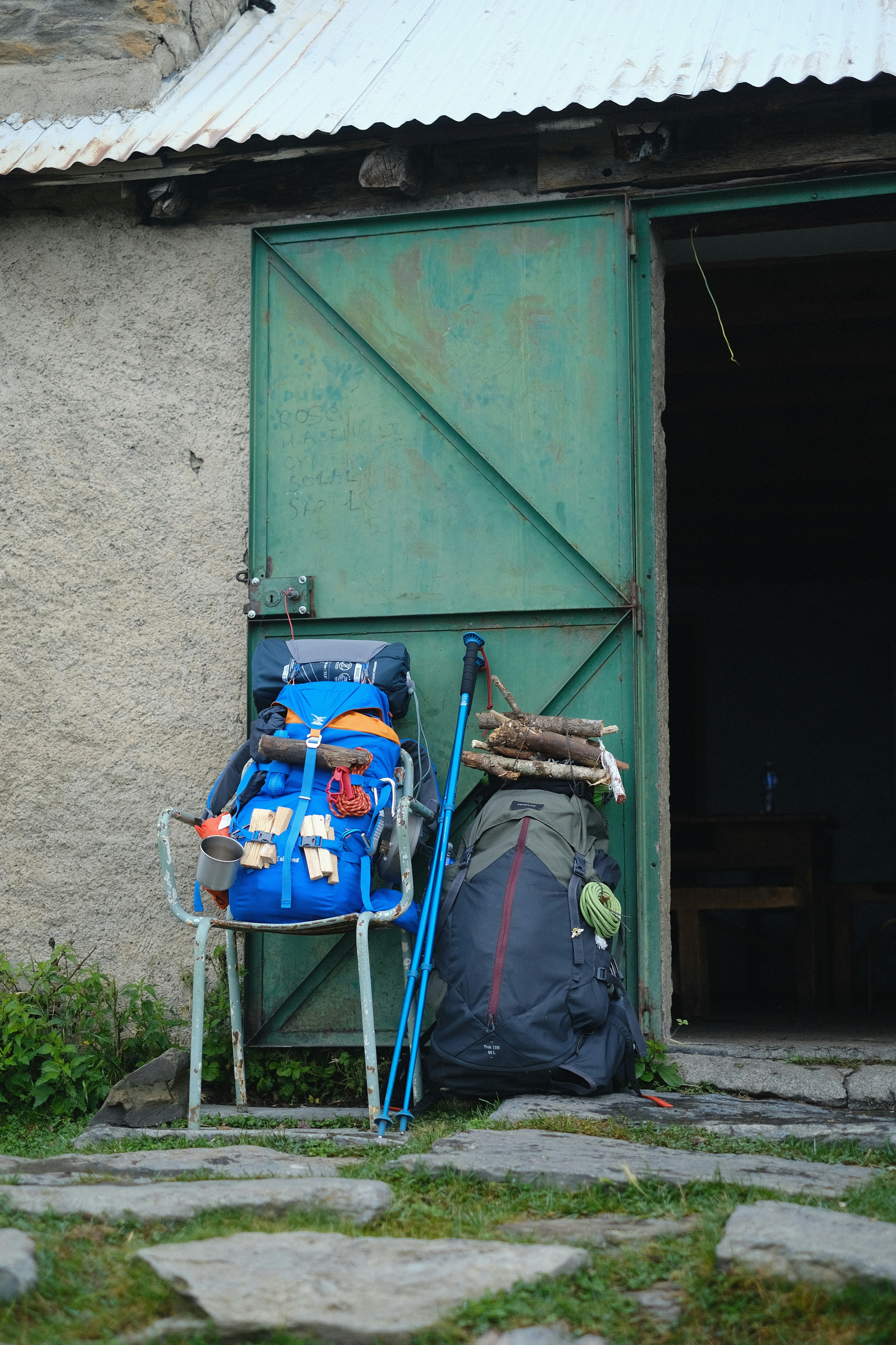 Sacs à dos et matériel de randonnée à l’extérieur d’un bâtiment rustique.